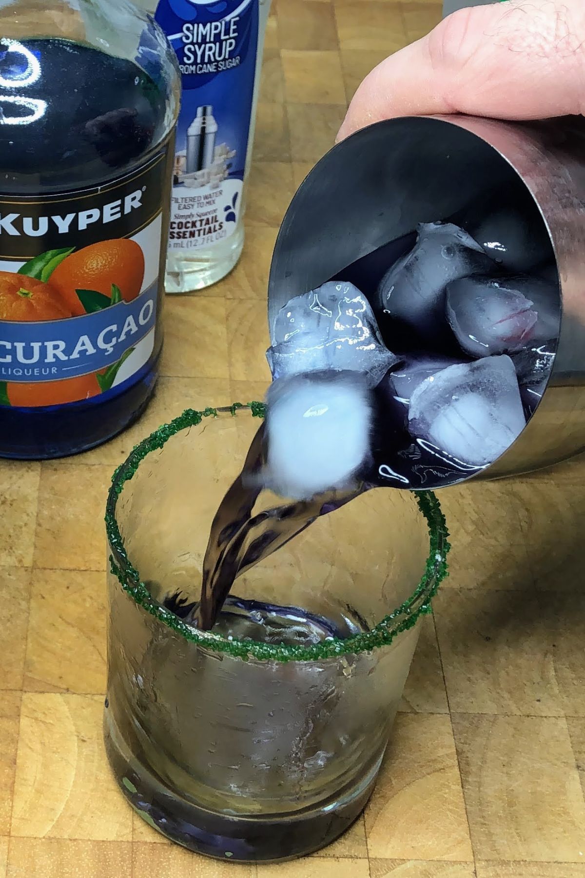Dumping a drunk witch drink from a shaker into a rocks glass.