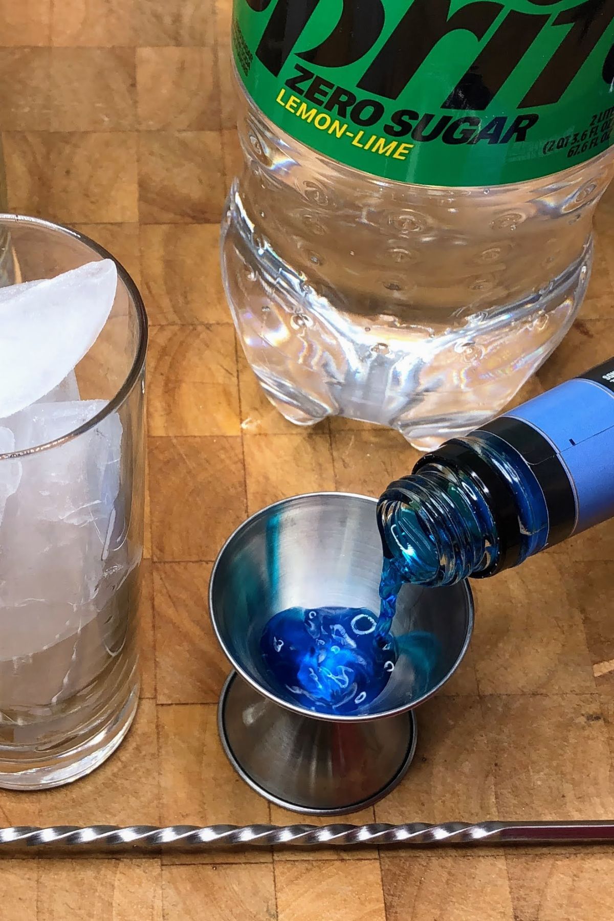 Pouring blue curacao into a jigger.