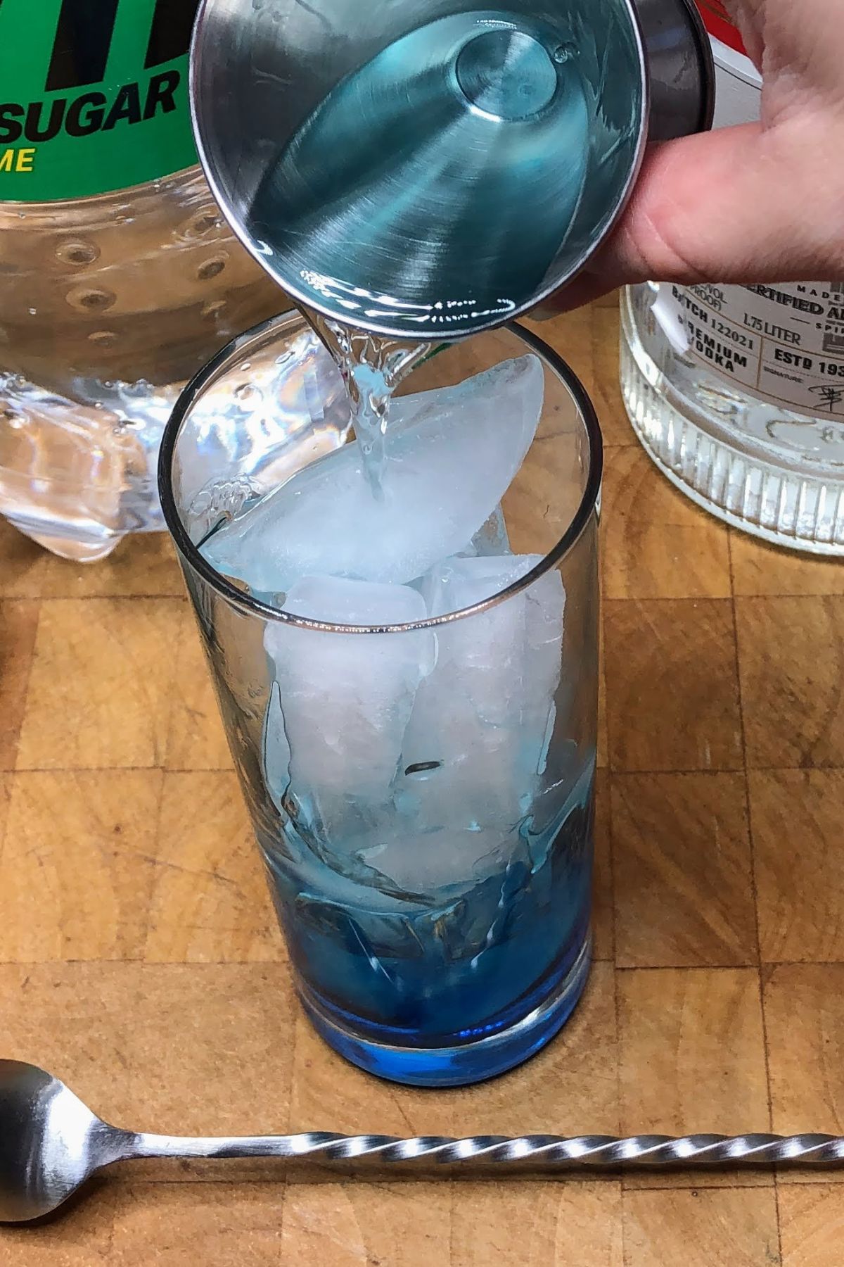 Pouring vodka from a jigger into a glass.
