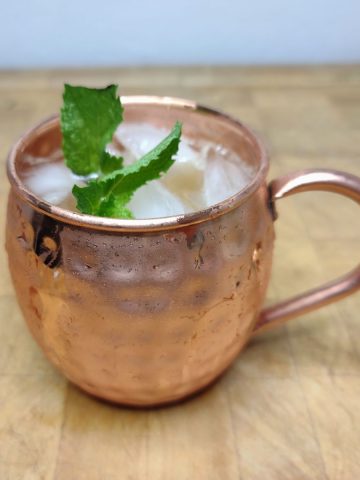 French mule on a wooden table with mint in the mug.