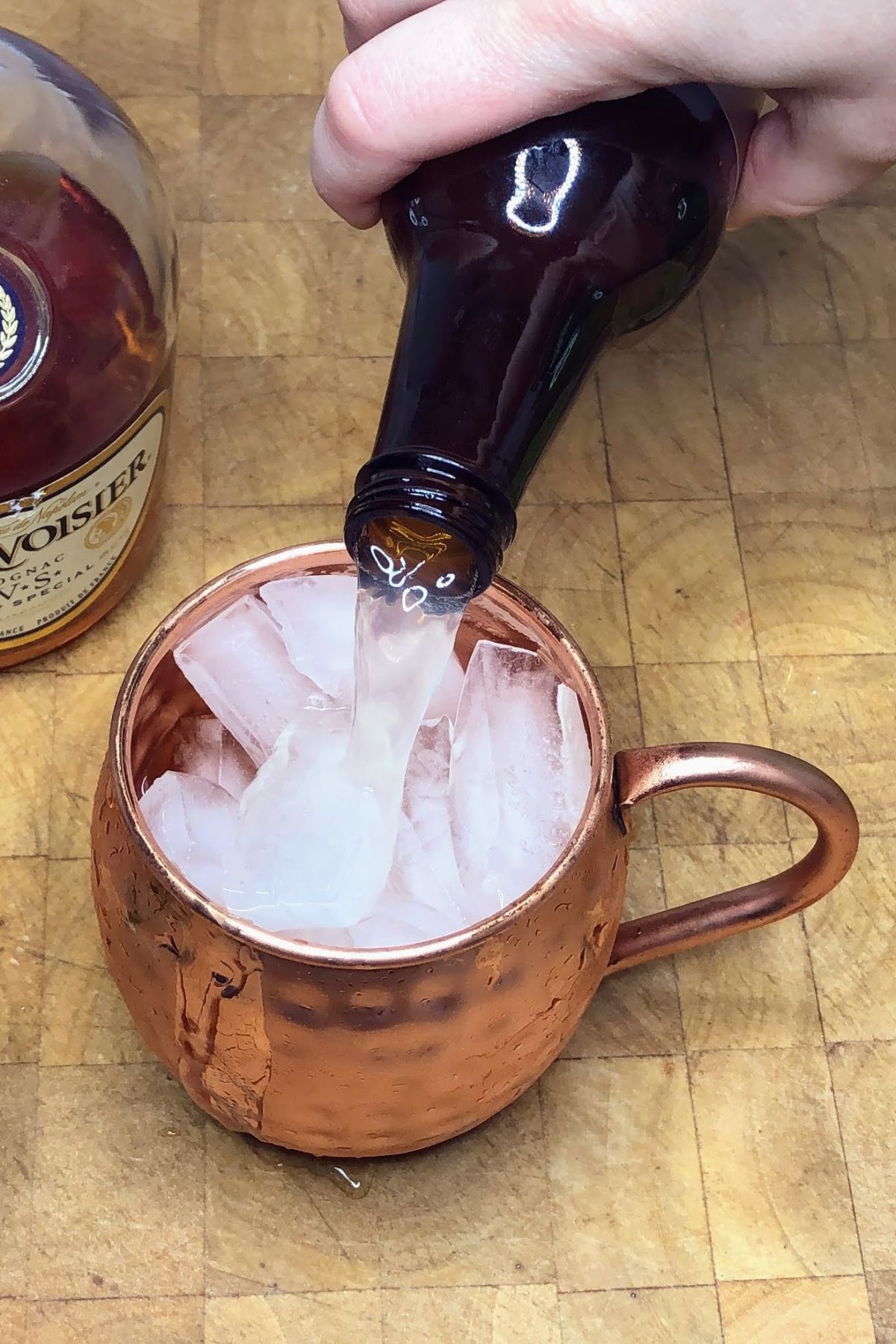 Pouring ginger beer into a copper mug.
