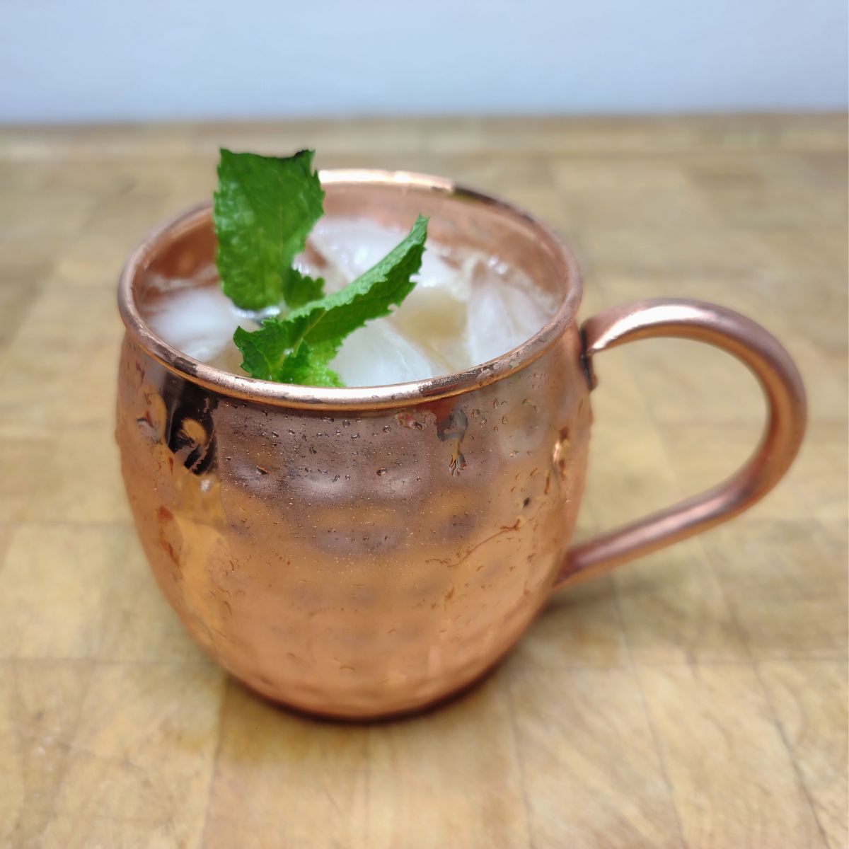 French mule on a wooden table with mint in the mug.