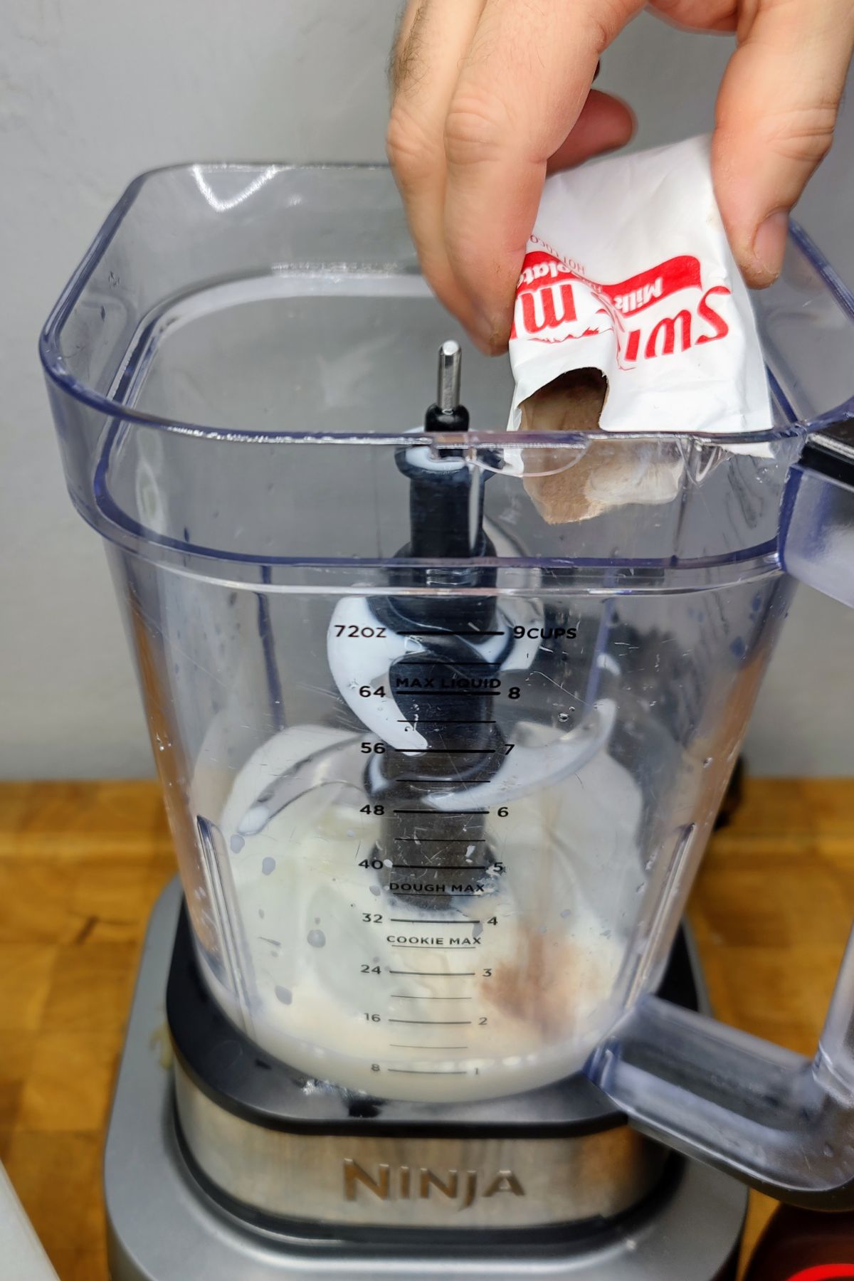 Pouring hot chocolate mix into a blender.