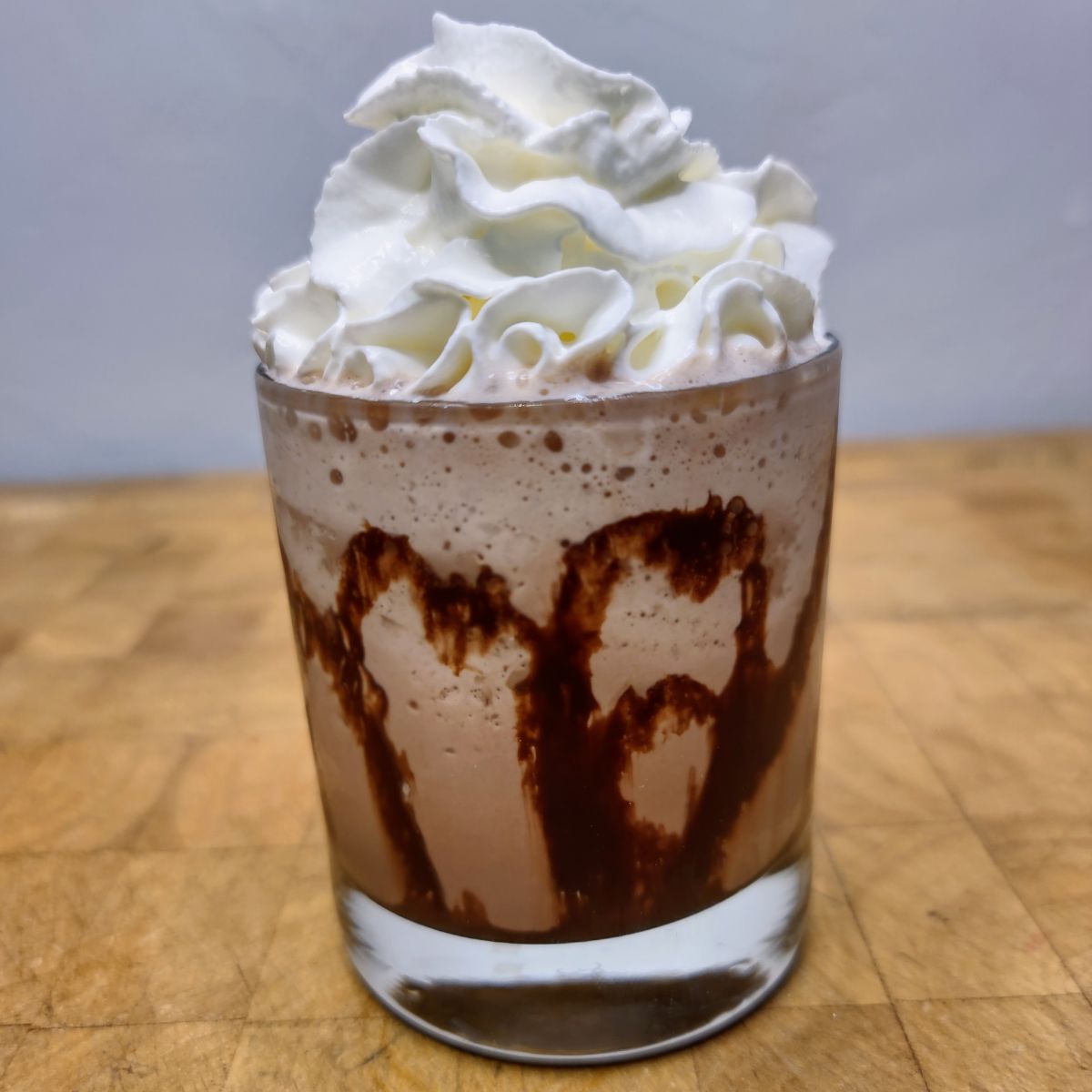 Frozen hot chocolate with whipped cream on top on a wooden table.