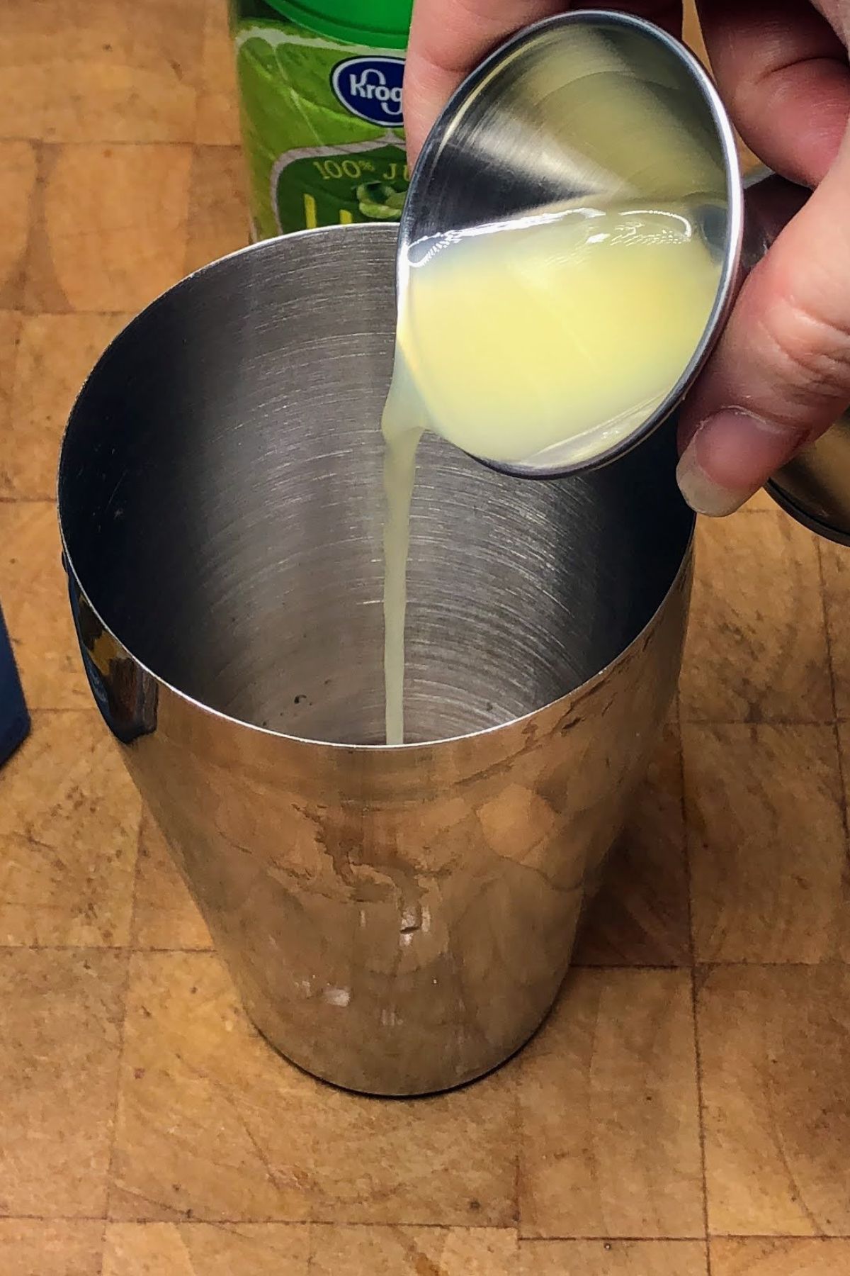 Pouring lime juice into a shaker.