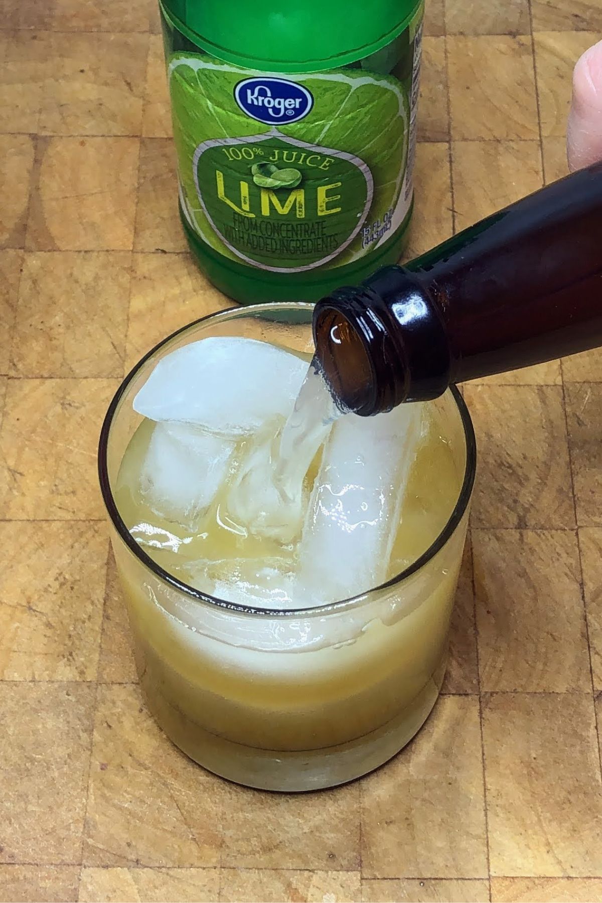 Pouring ginger beer into a rocks glass.