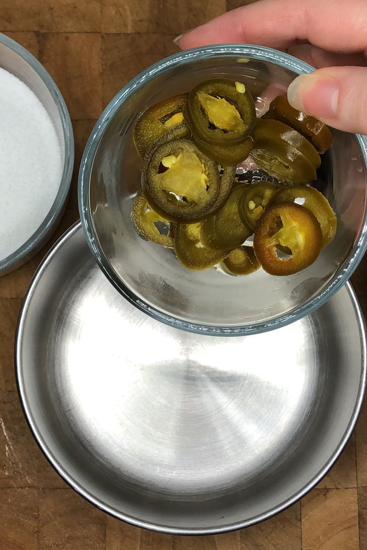 Pouring jalapeno slices into a pot.