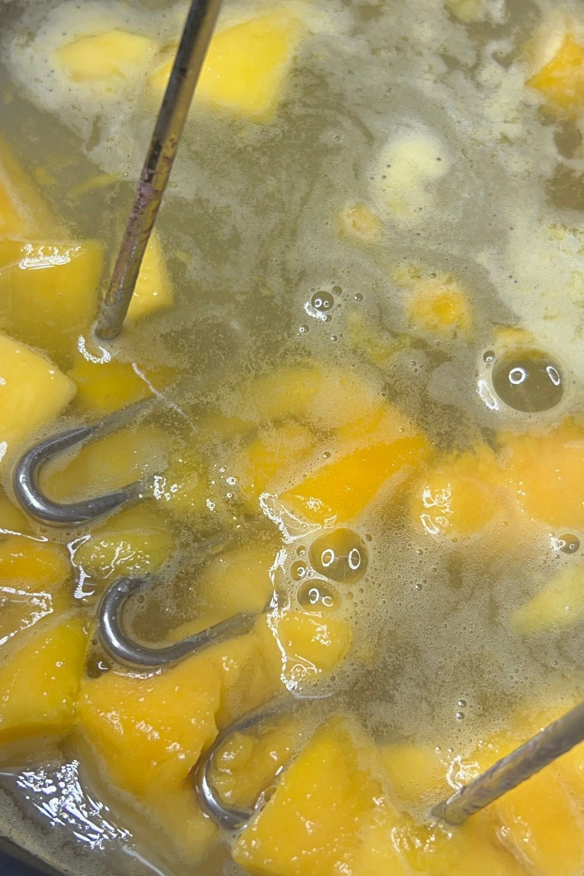 Mashing mangos in water while heating.