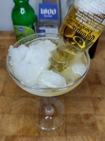 Mexican bulldog with a coronita bottle in the glass and ingredients in the background.