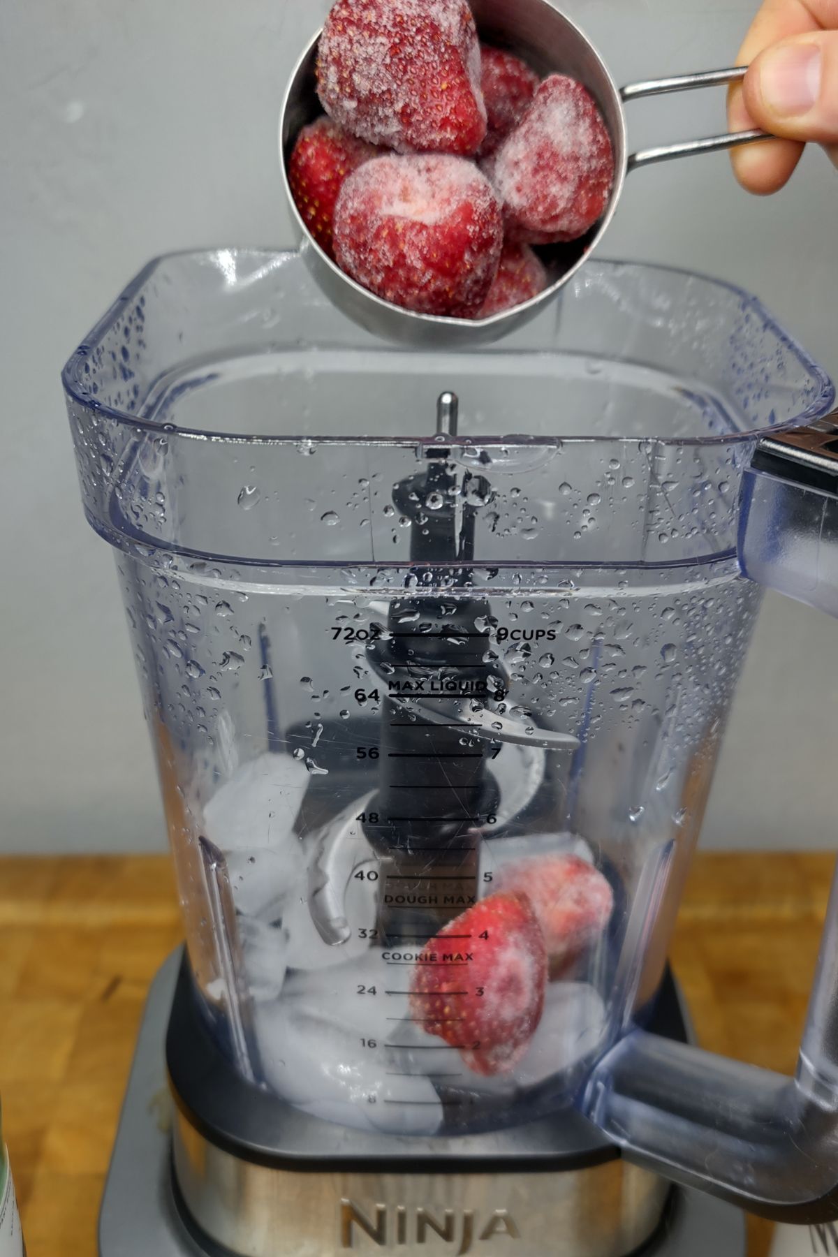 Adding strawberries to a blender.