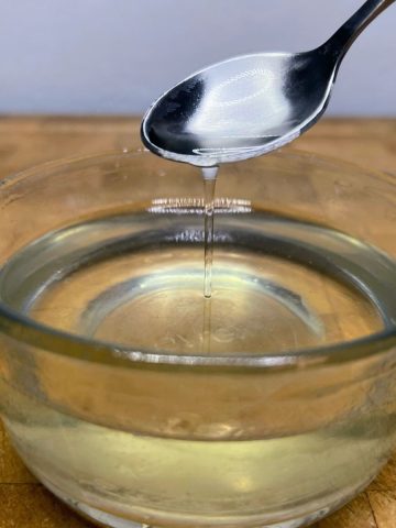 Mint simple syrup being scooped by a spoon.