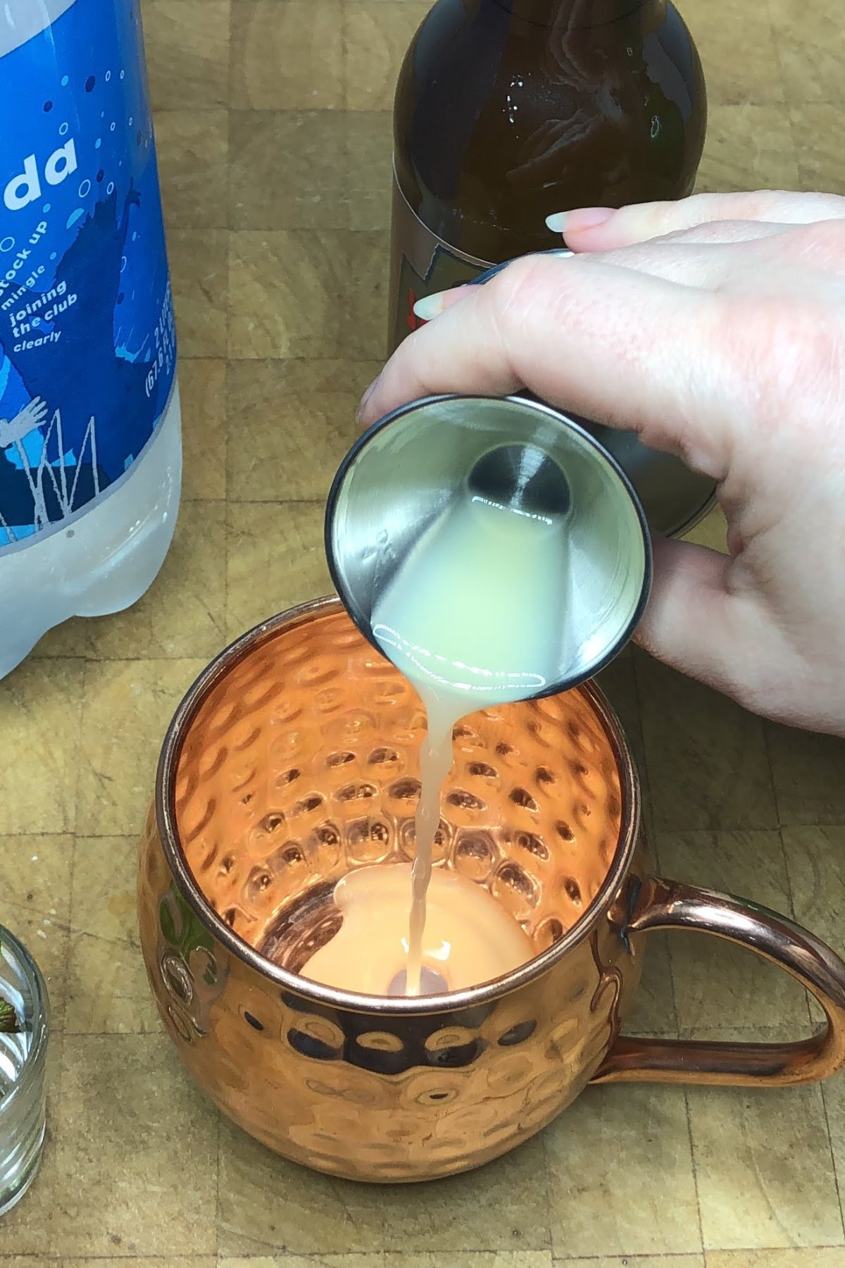 Pouring lime juice into a copper mug.