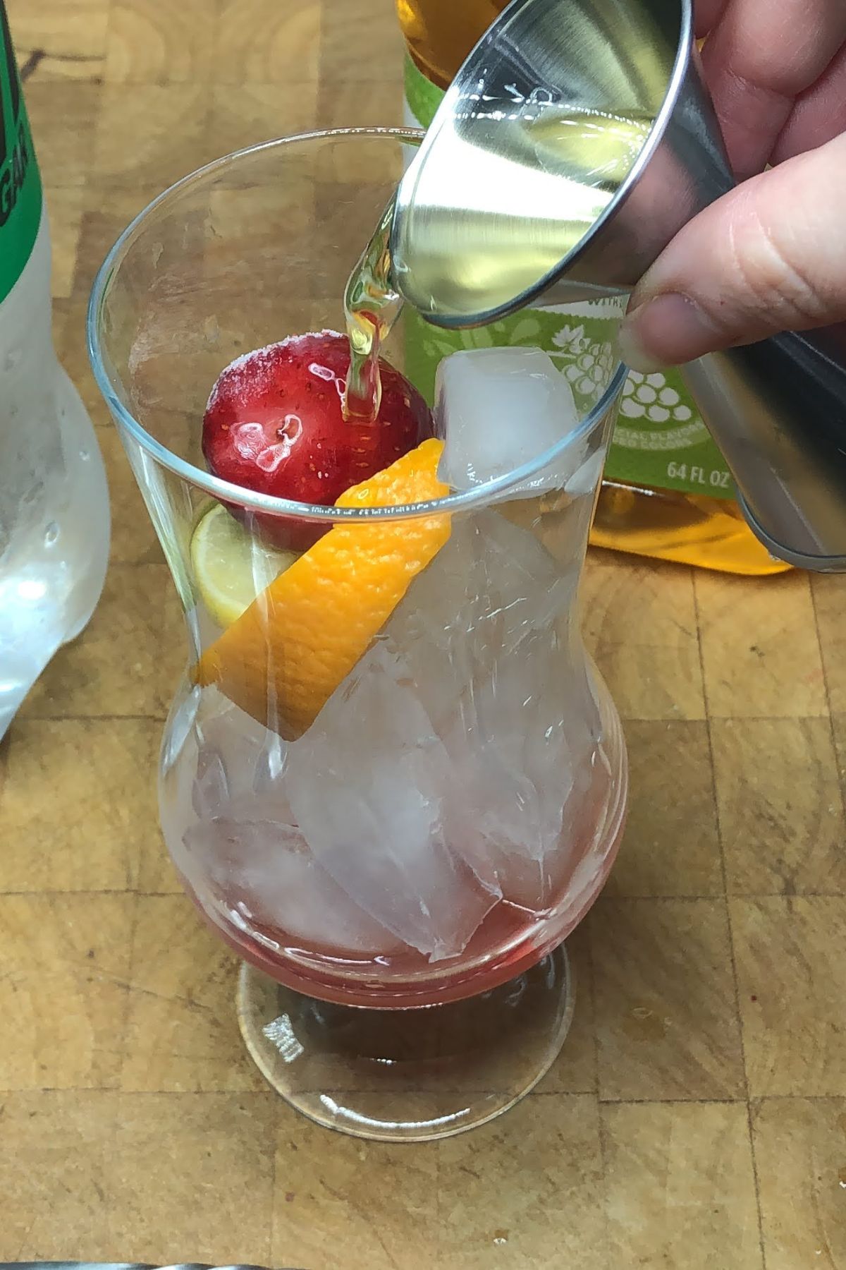 Pouring grape juice into a hurricane glass.