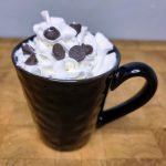 Oat milk hot chocolate with whipped cream and chocolate chips on top.