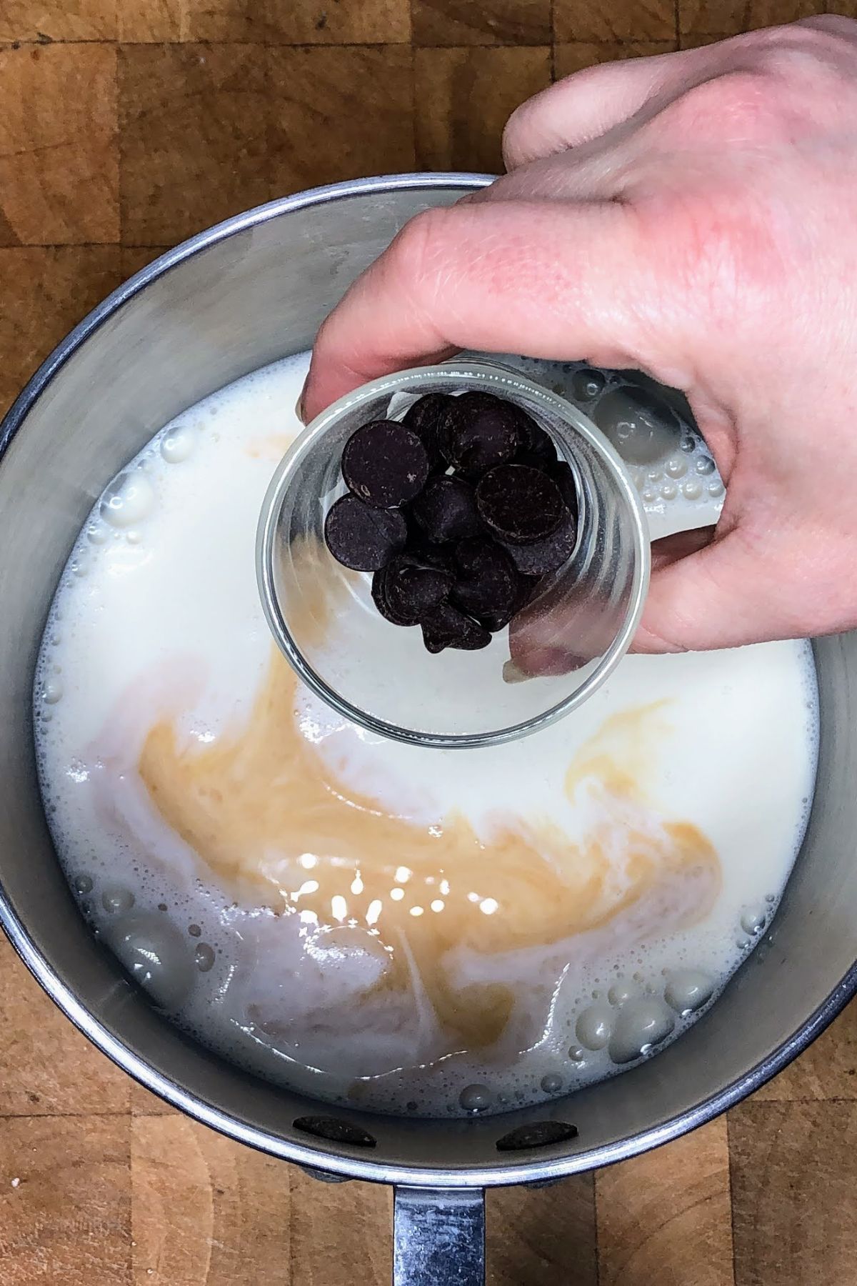 Pouring chocolate chips into a pot.