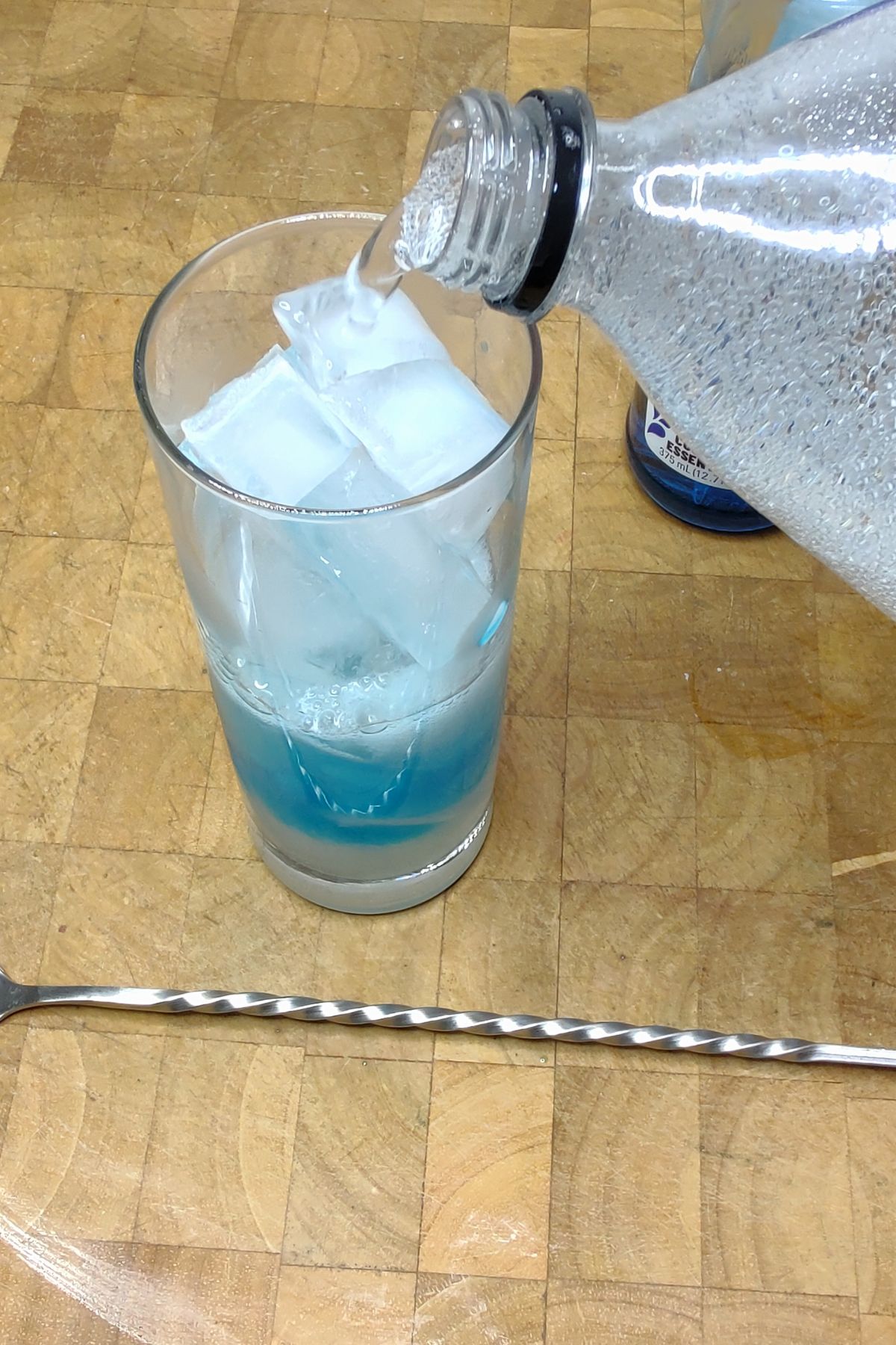 Pouring club soda from a bottle into a glass.