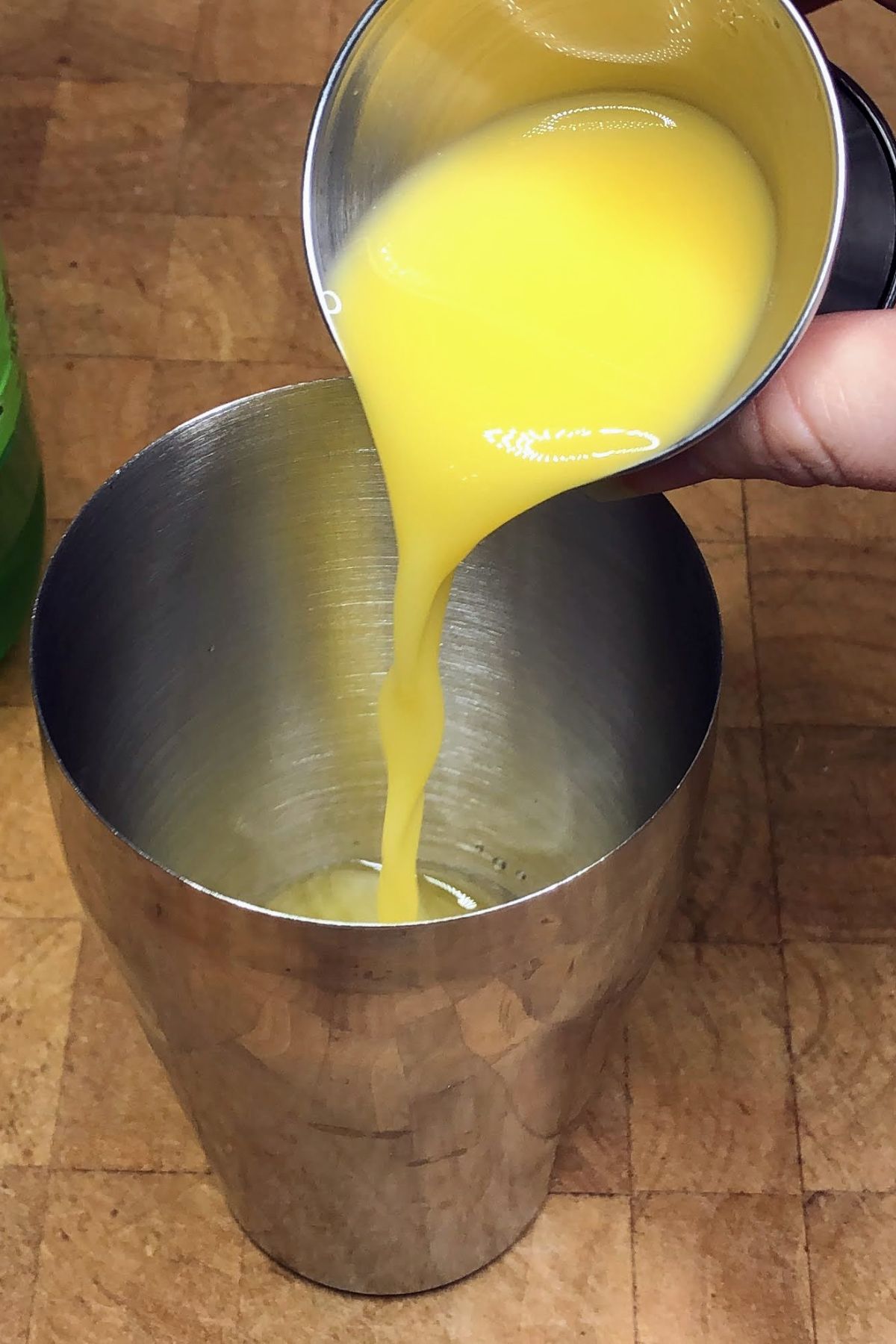 Pouring orange juice into a shaker.