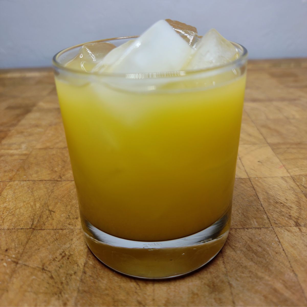 Orange mocktail in a rocks glass on a wooden table.