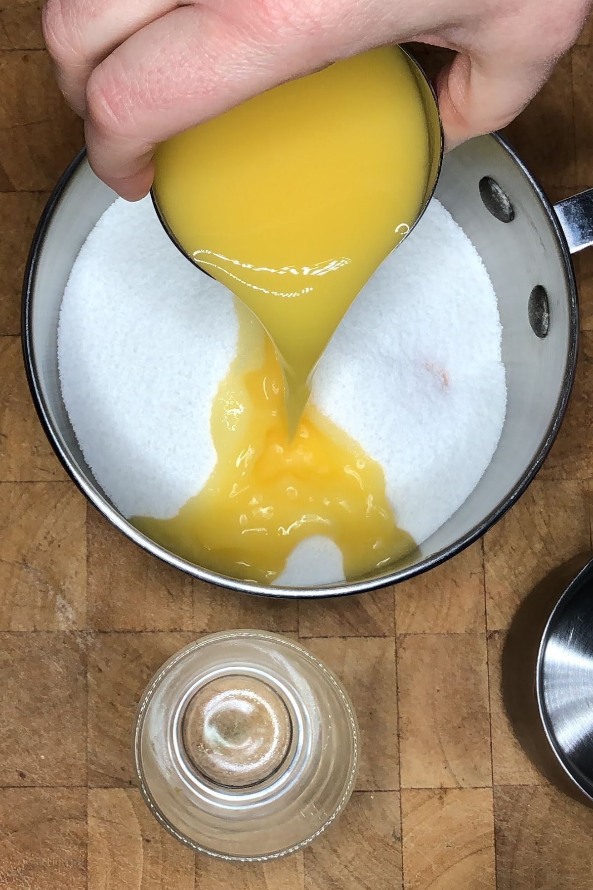 Pouring orange juice into a pot with sugar.