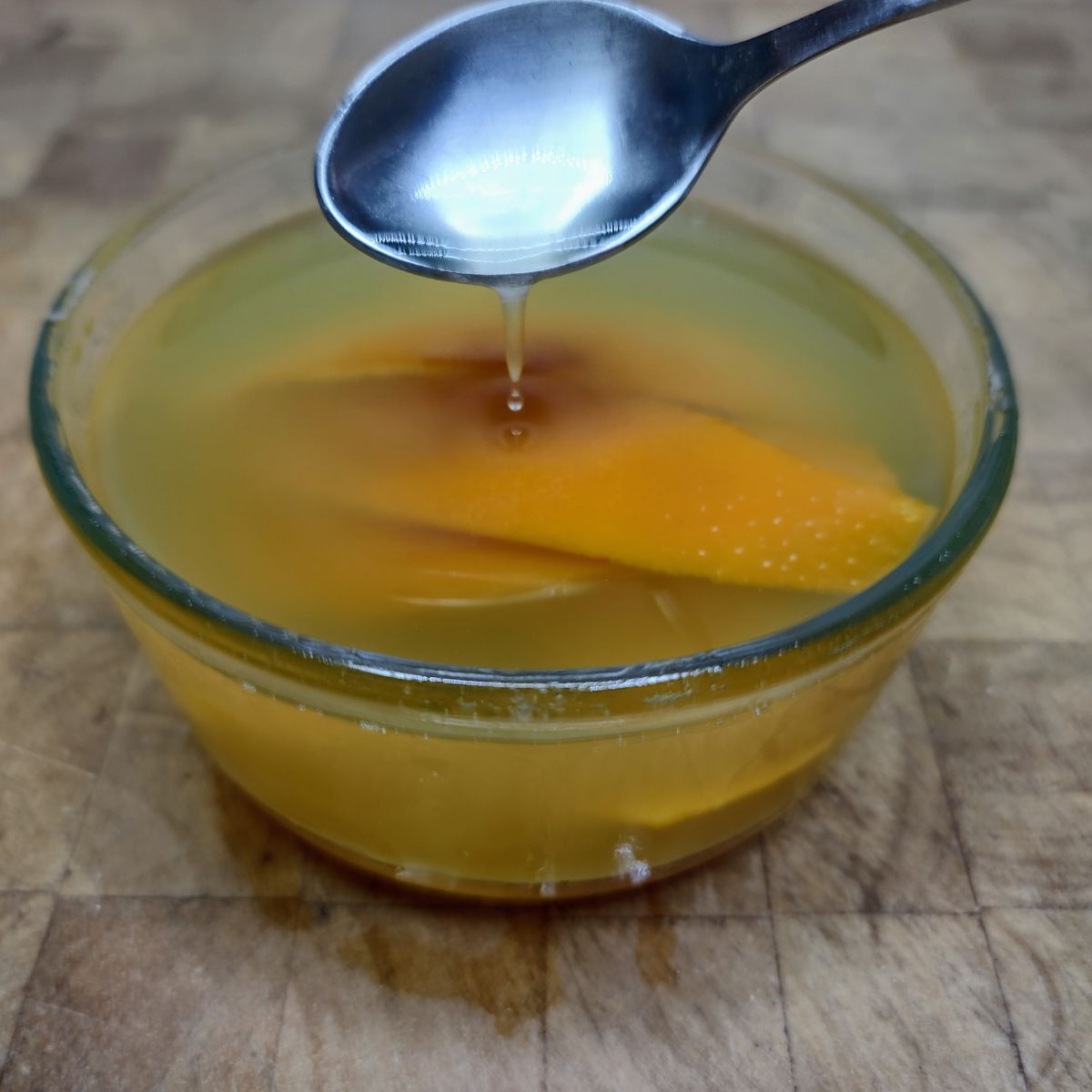 Orange simple syrup being scooped by a spoon.