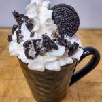 Oreo hot chocolate in a mug with crumbled oreos and whipped cream.