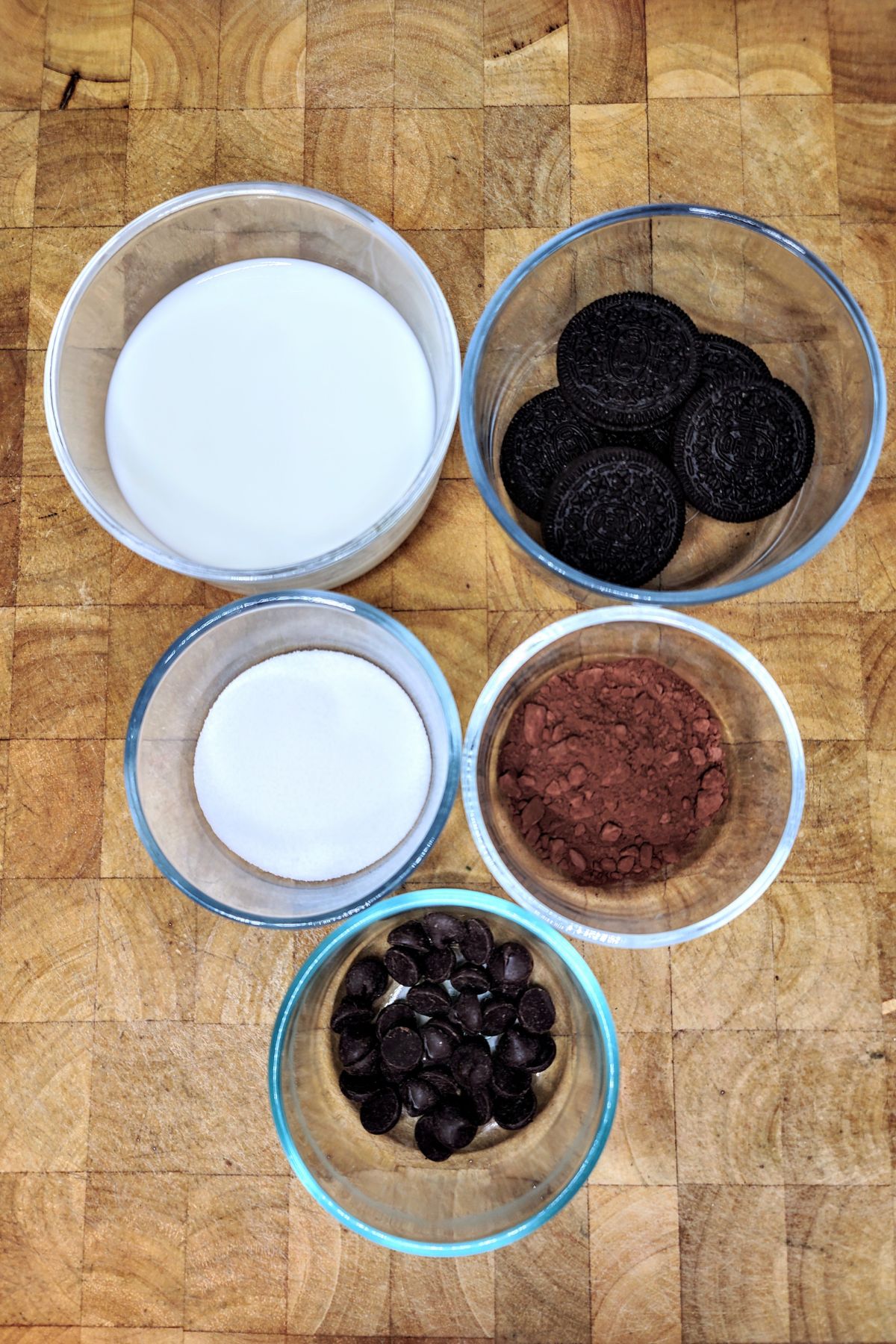 Bowls of chocolate chips, cocoa powder, oreos, milk and sugar.