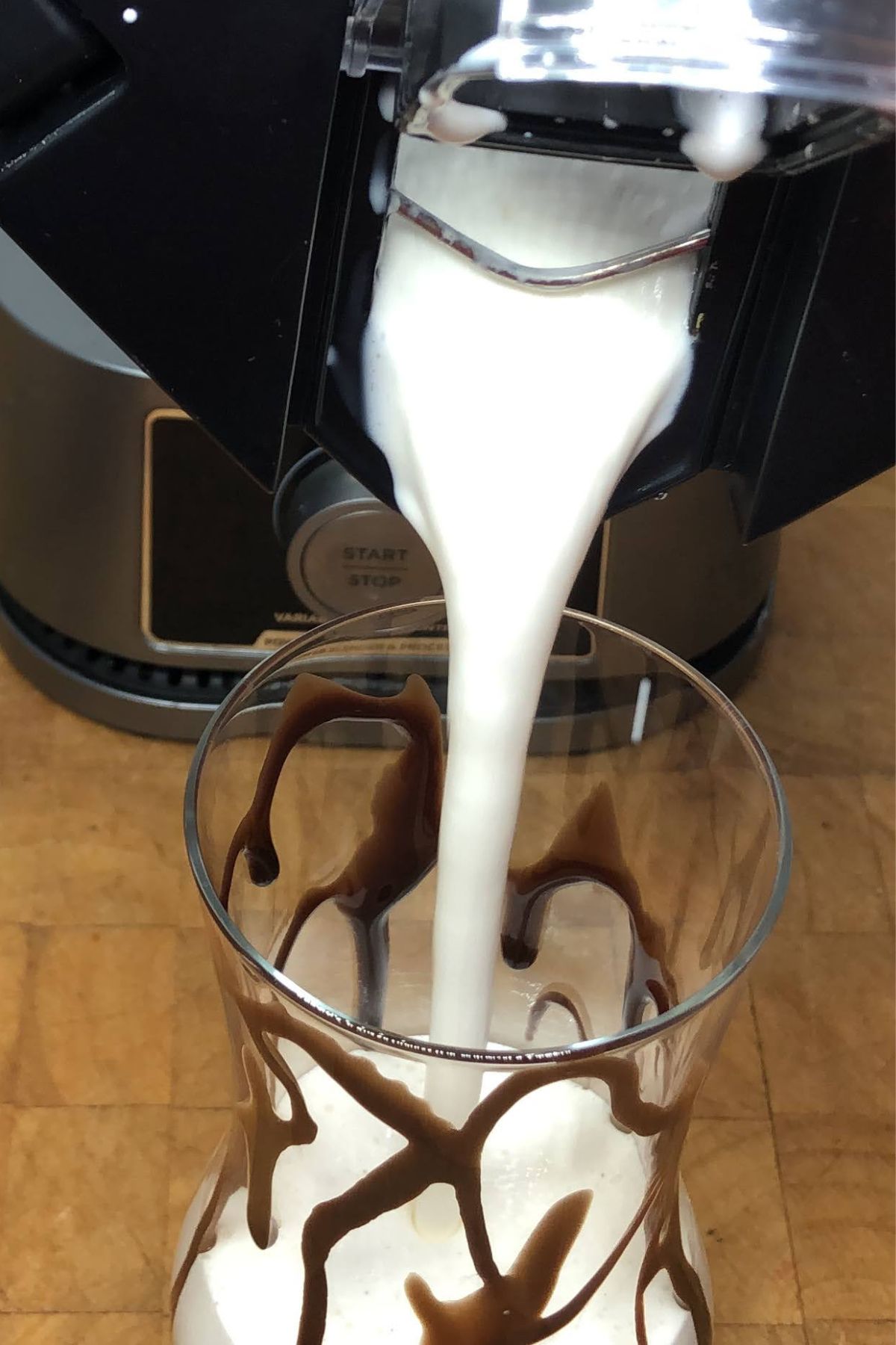Pouring peanut butter whiskey milkshake from blender into a glass.