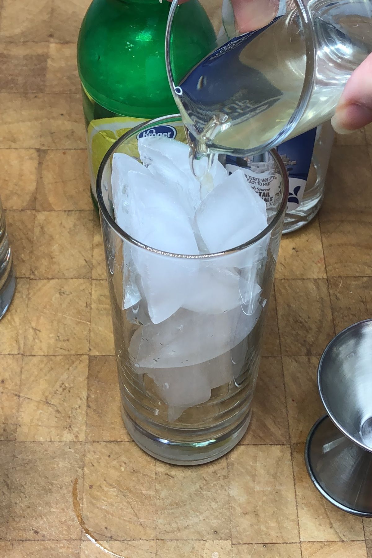 Pouring pickle juice into a highball glass.