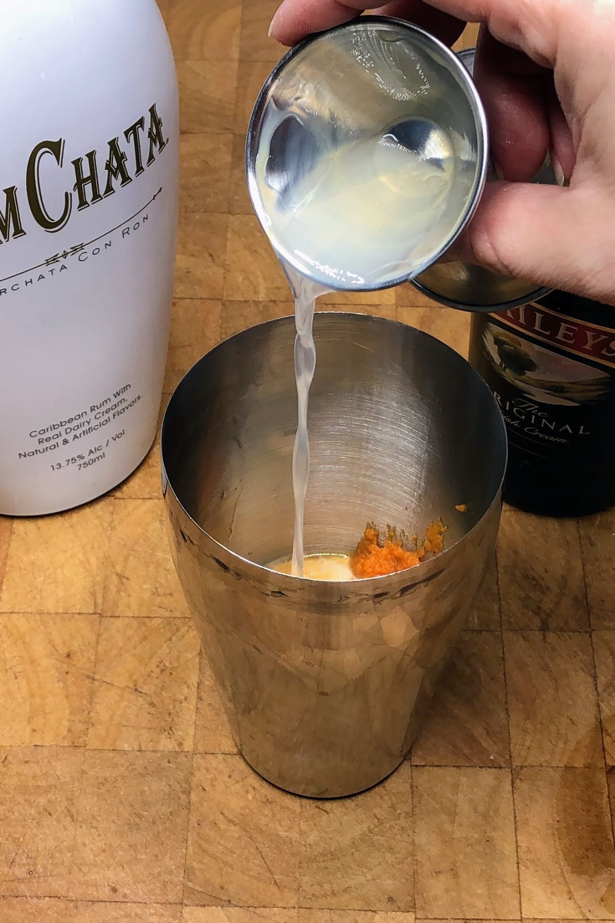 Adding vanilla vodka into a shaker.