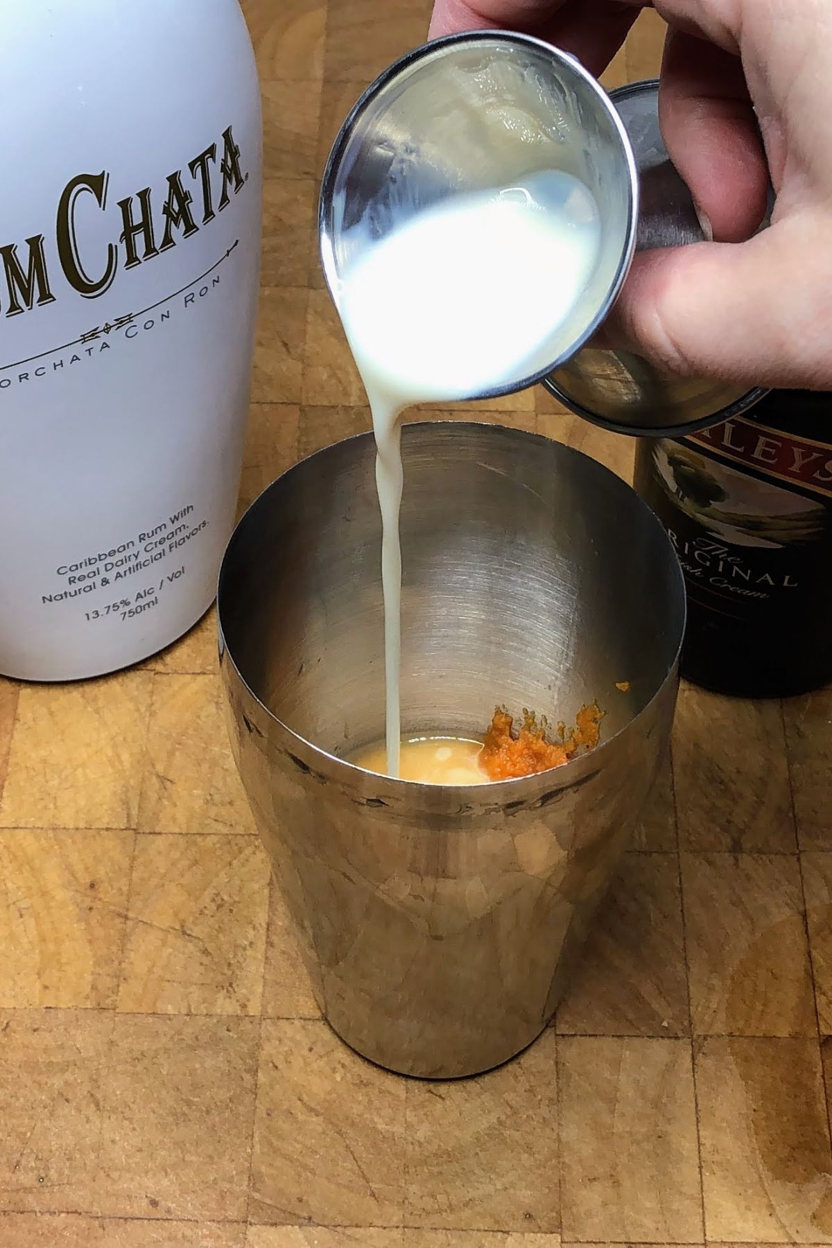 Adding rumchata into a shaker.