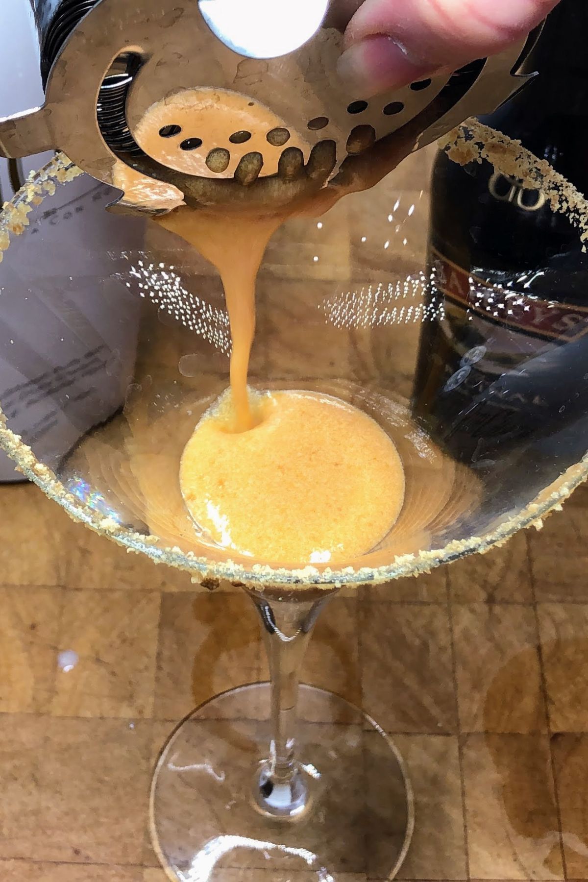 Pouring pumpkin pie martini from the shaker into the glass.