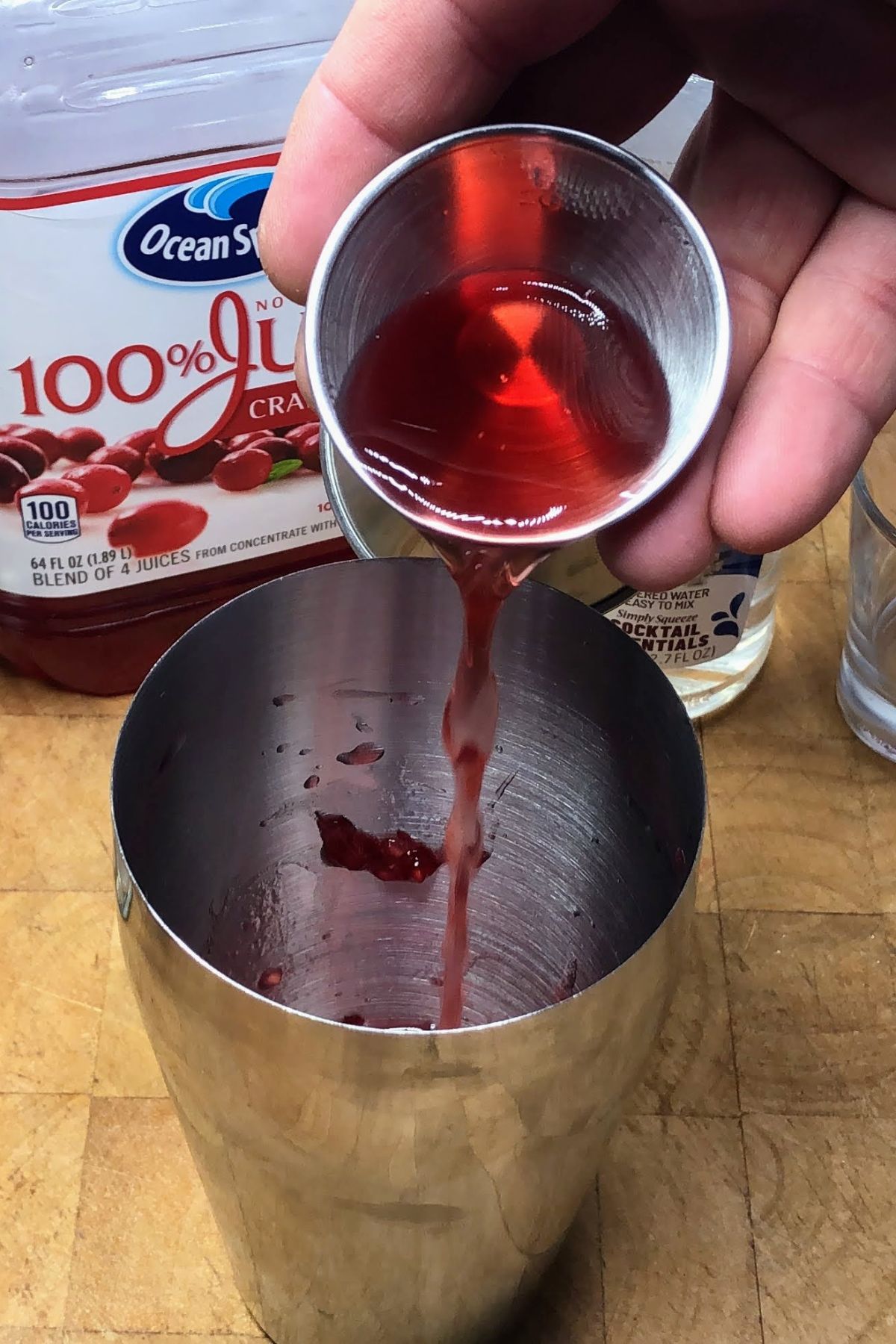 Pouring cranberry juice into a shaker.