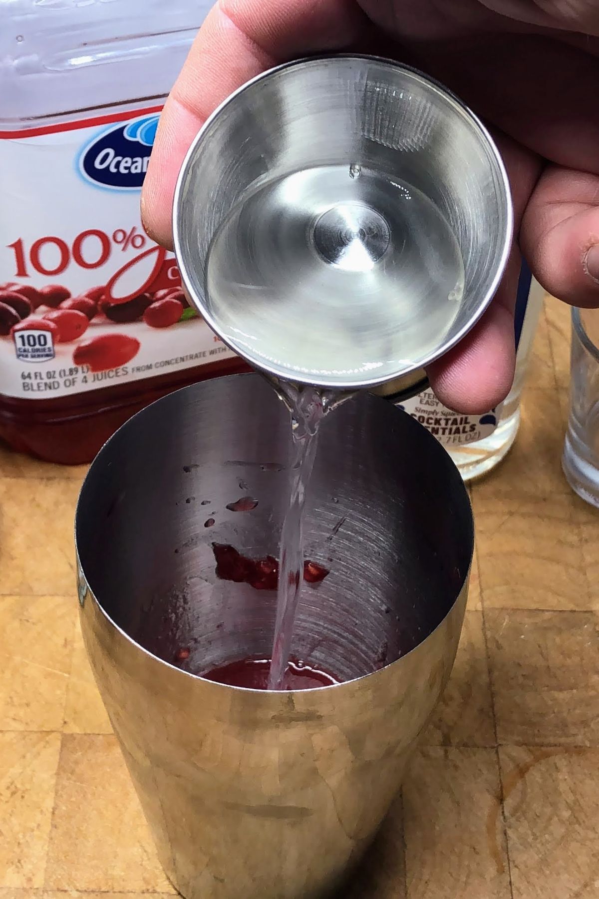 Pouring raspberry vodka into a shaker.
