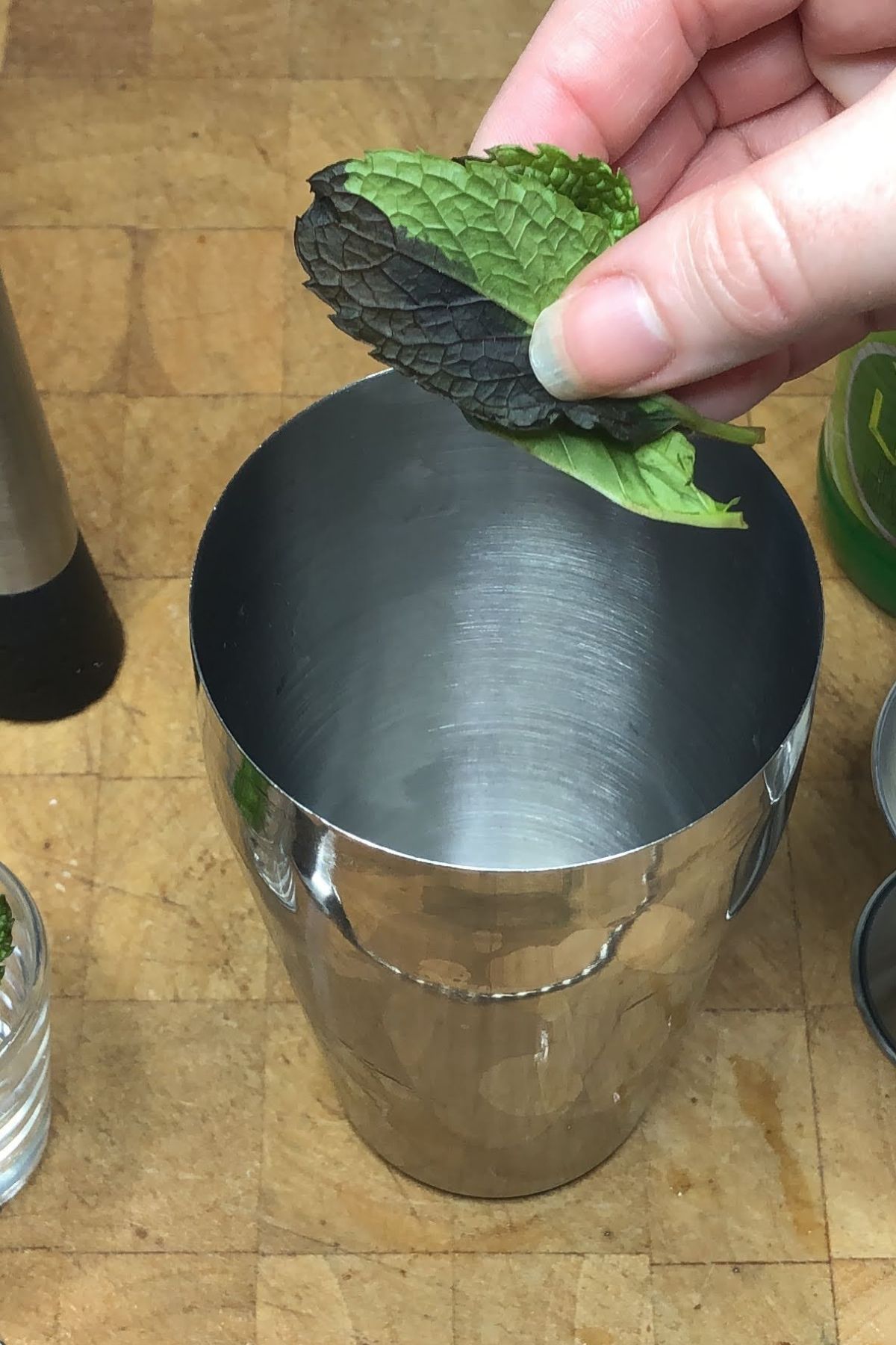 Adding mint leaves into a shaker.