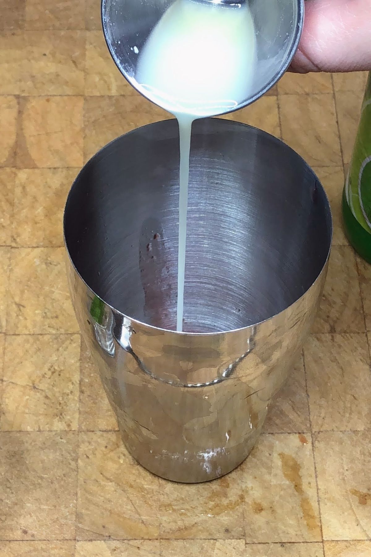 Pouring lime juice into a shaker.