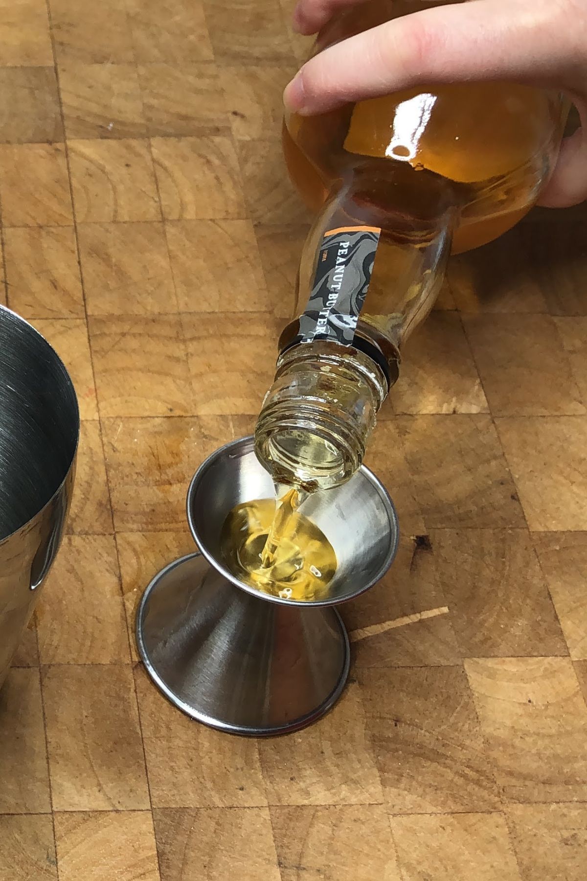 Measuring peanut butter whiskey into a jigger.