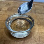 Simple syrup being scooped by a spoon.
