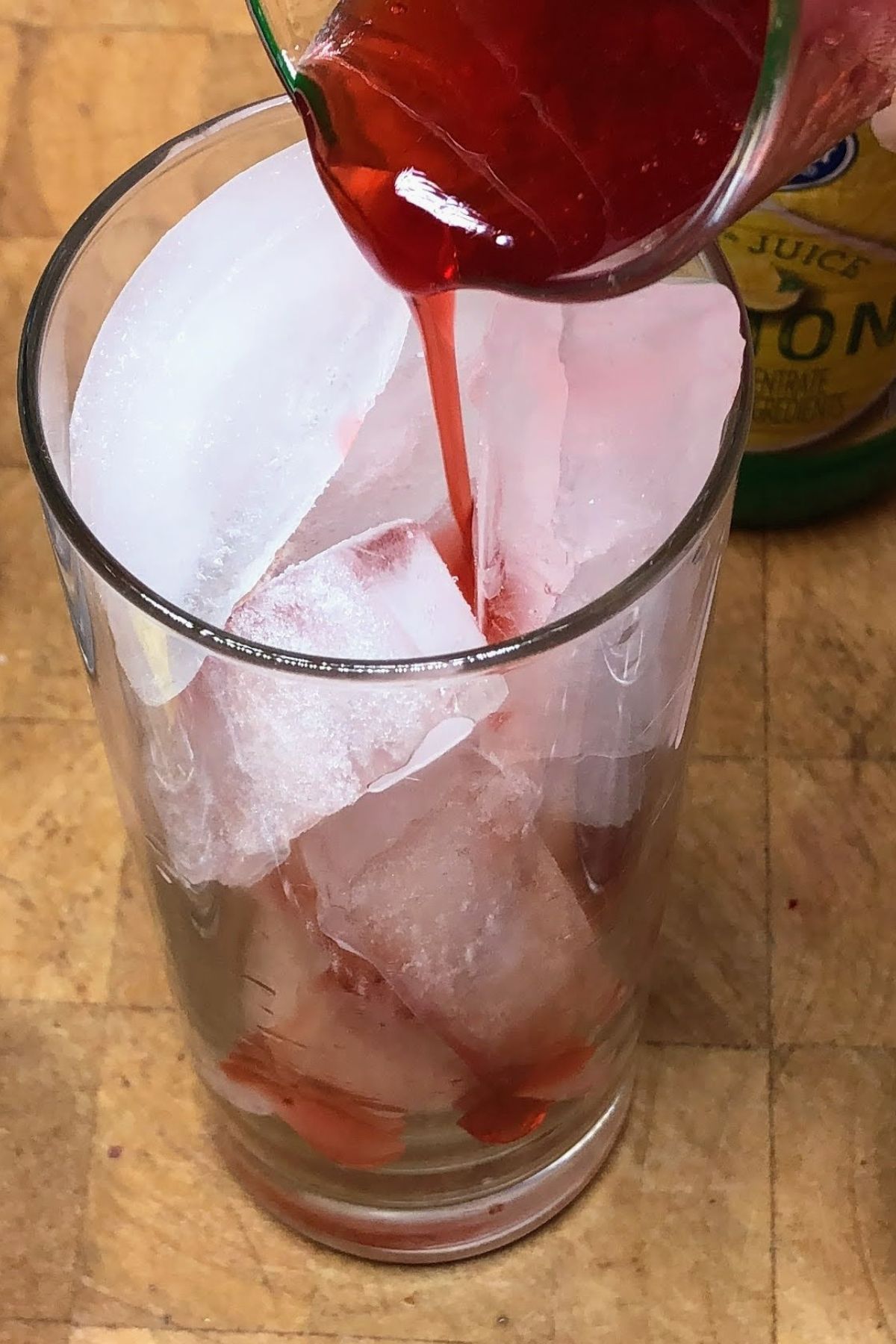 Pouring strawberry simple syrup into a glass.