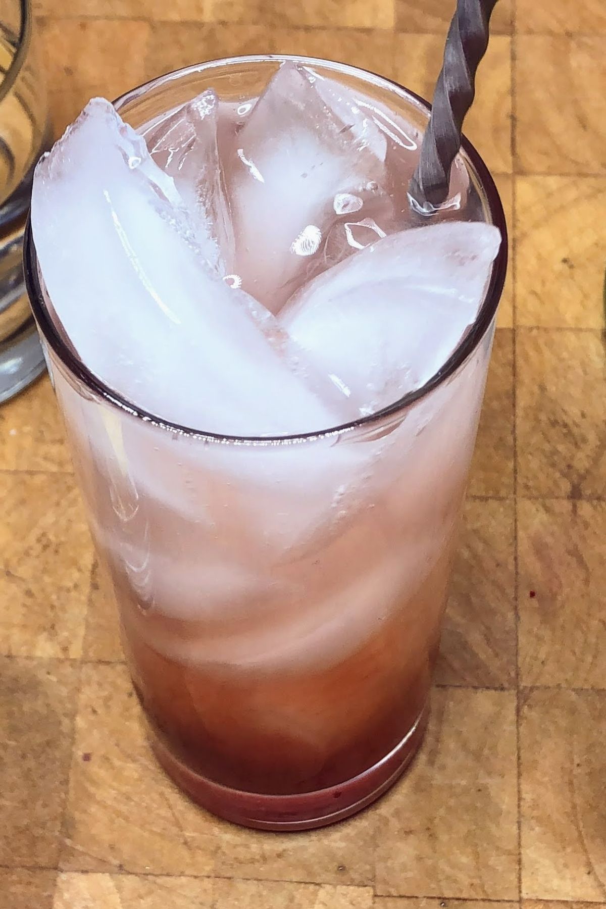 Stirring strawberry lemonade with a bar spoon.