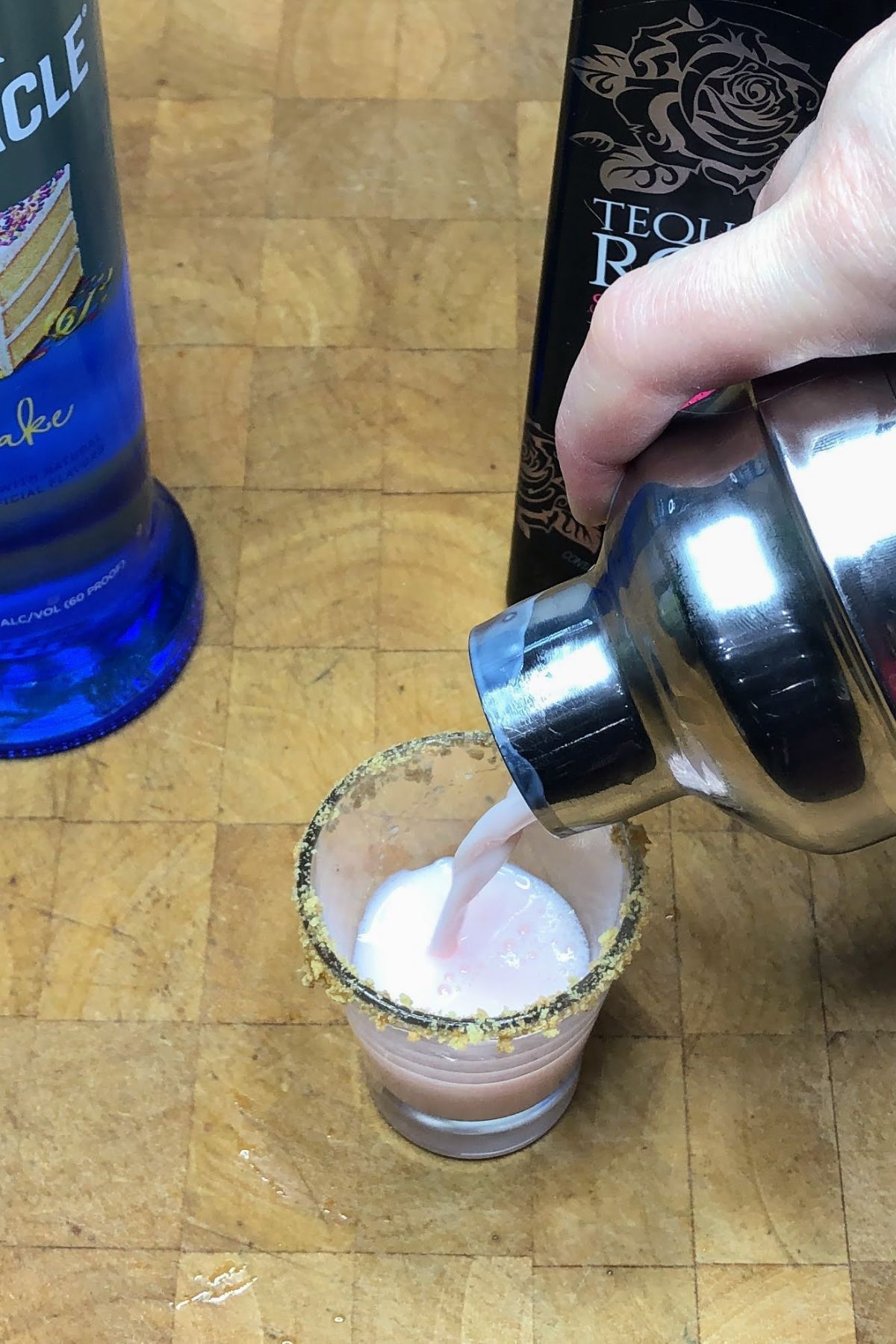 Pouring strawberry shortcake shot from a shaker into a shot glass.