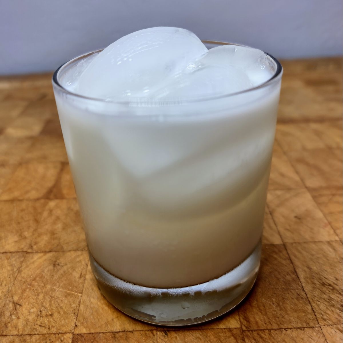 Vanilla milk in a rocks glass on a wooden table.