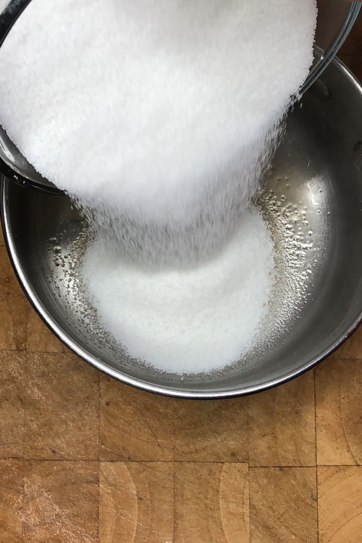 Pouring sugar into a saucepan with vanilla.