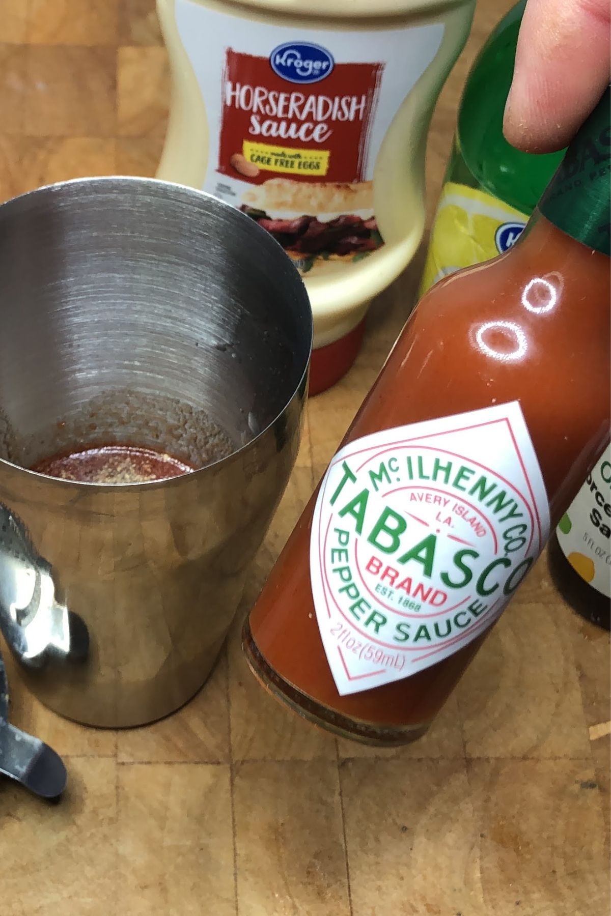Bottle of tabasco sauce next to a shaker.