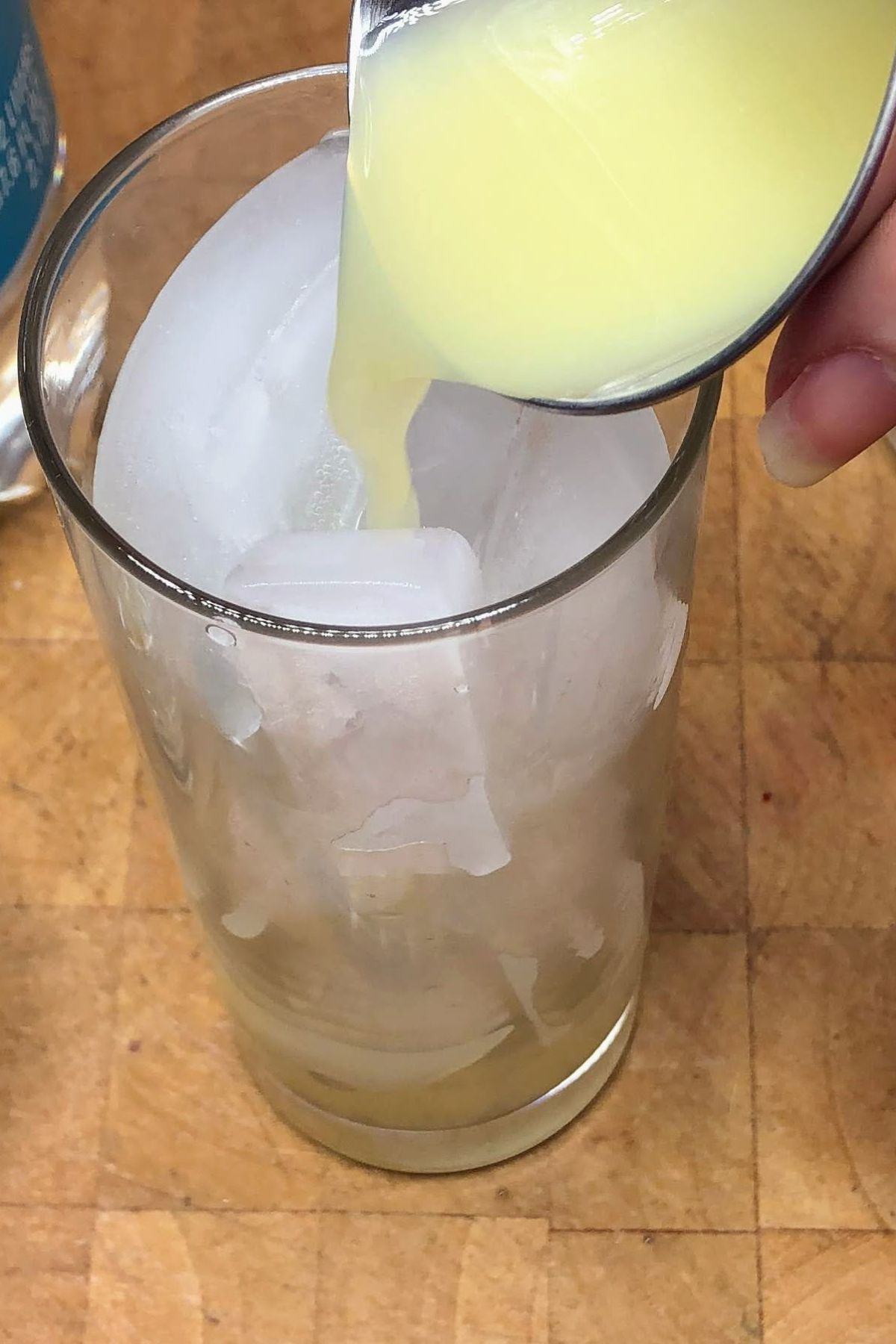 Pouring lime juice from a jigger into a glass.