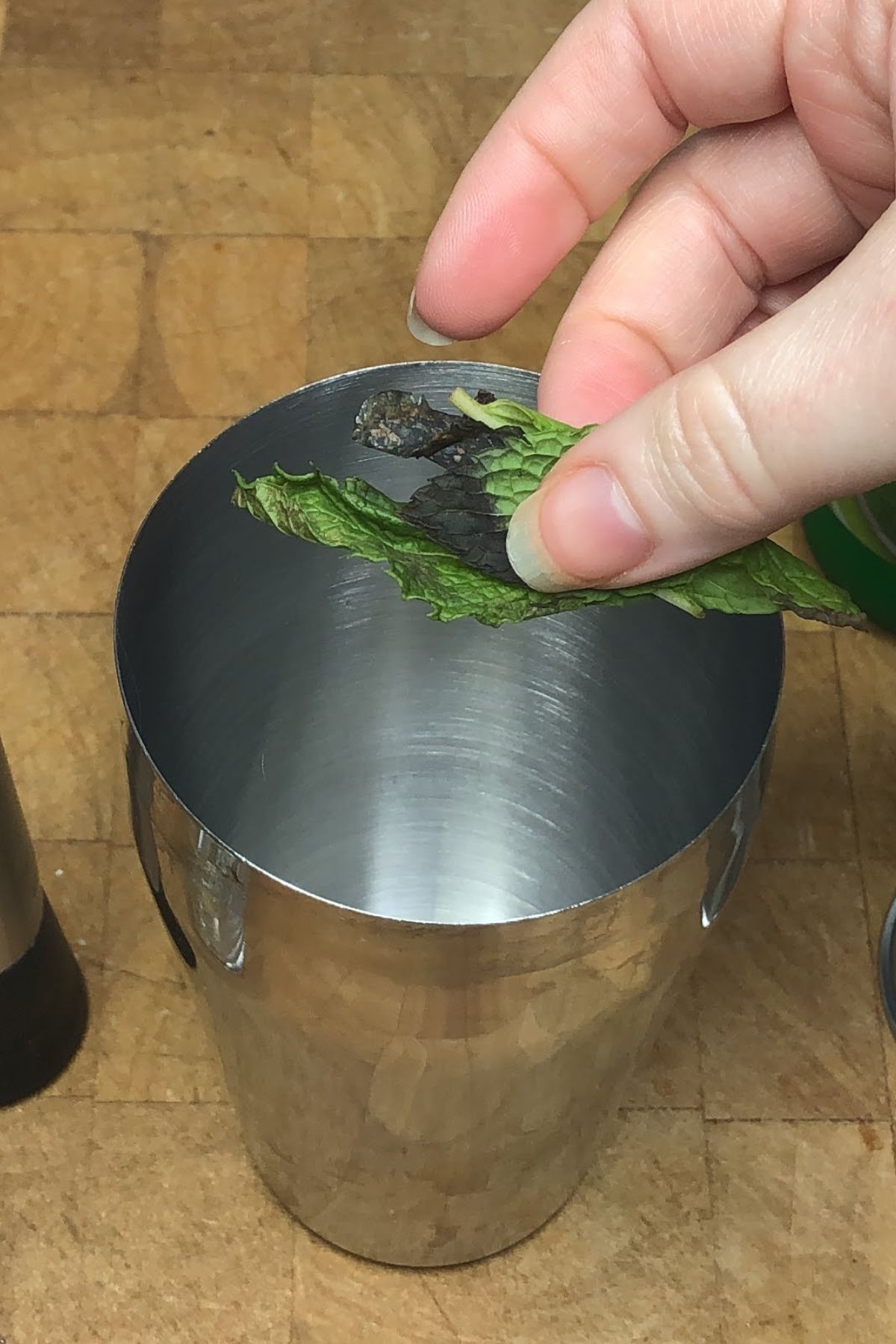 Tossing mint leaves into a shaker.