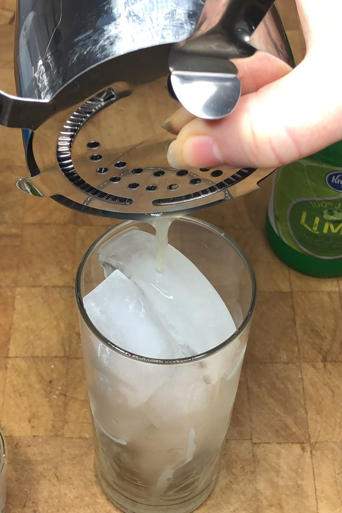 Pouring a virgin mojito from a shaker into a glass.