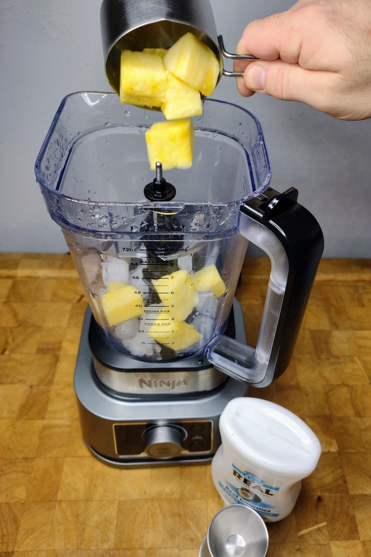 Dumping pineapple into a blender.