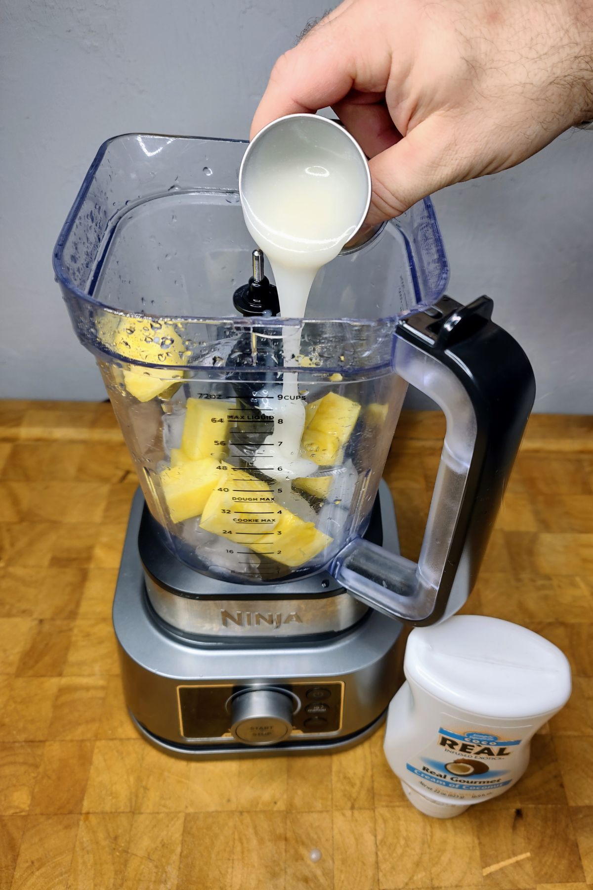 Pouring cream of coconut into a blender.