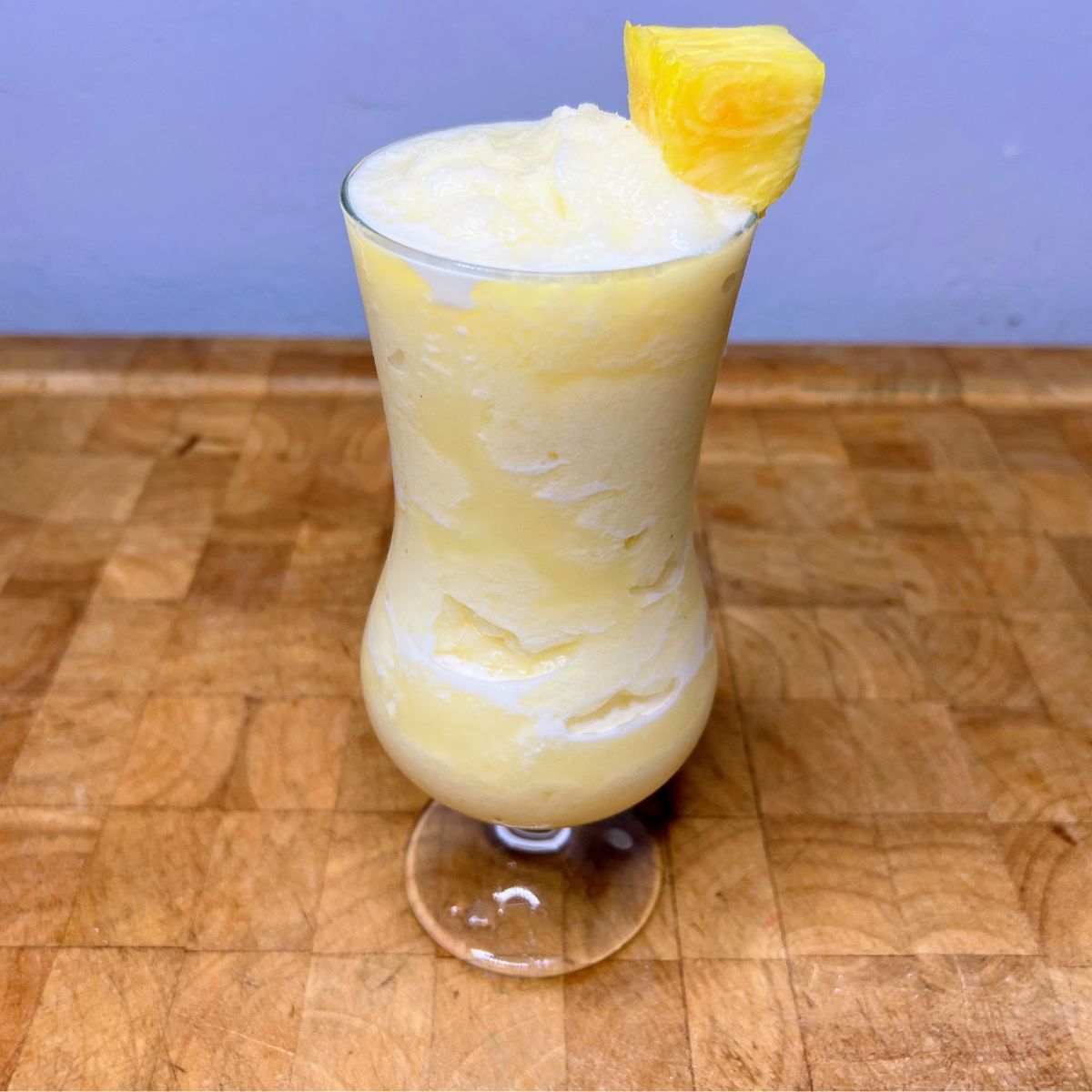 Virgin pina colada in a hurricane glass with slice of pineapple on the rim.