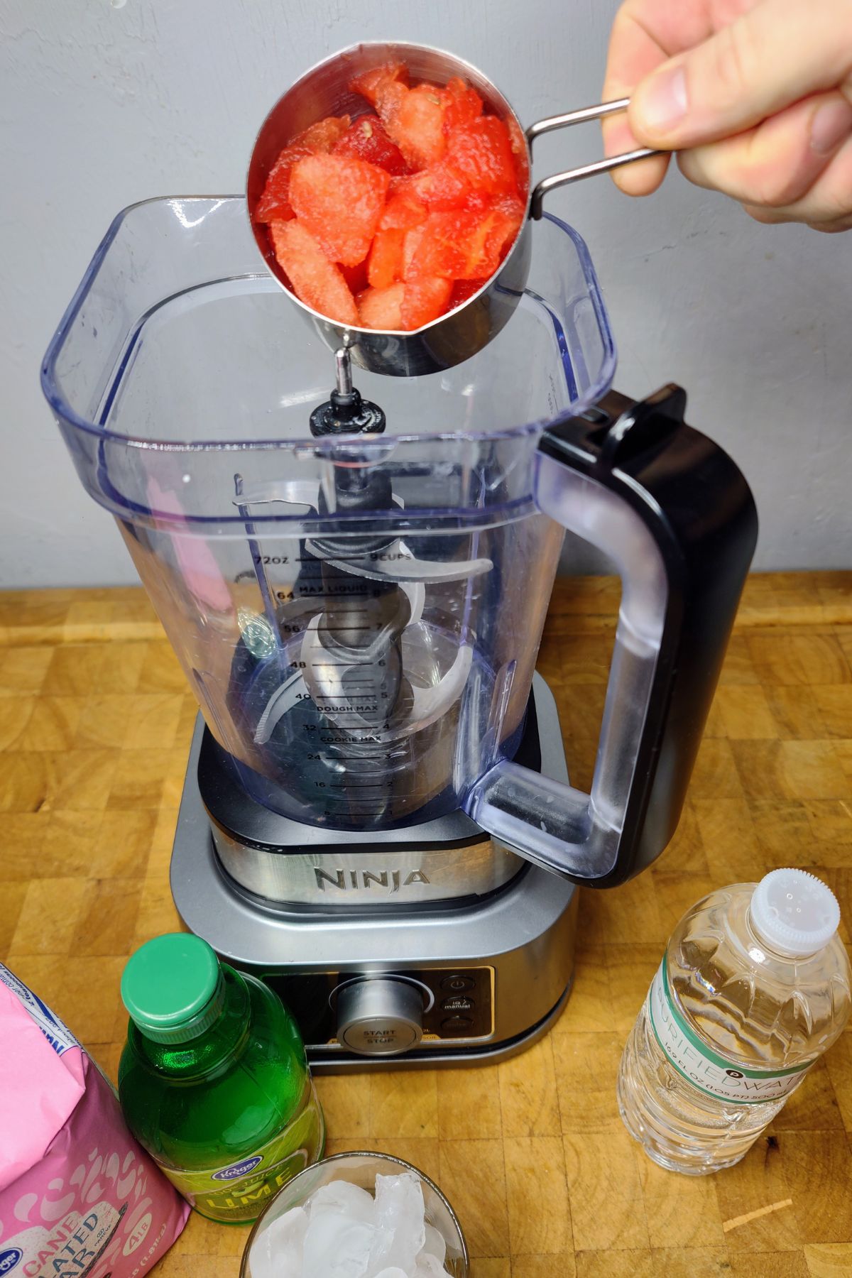 Pouring chunks of watermelon into a blender.